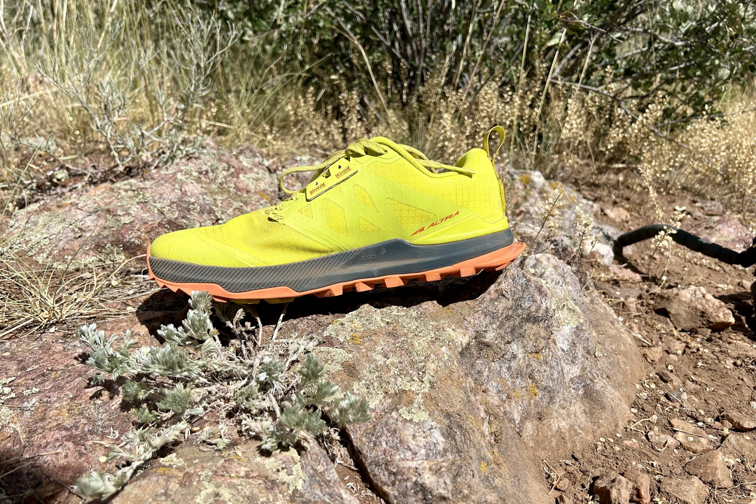 A picture of a hiking shoe staged on a rock in a desert setting.