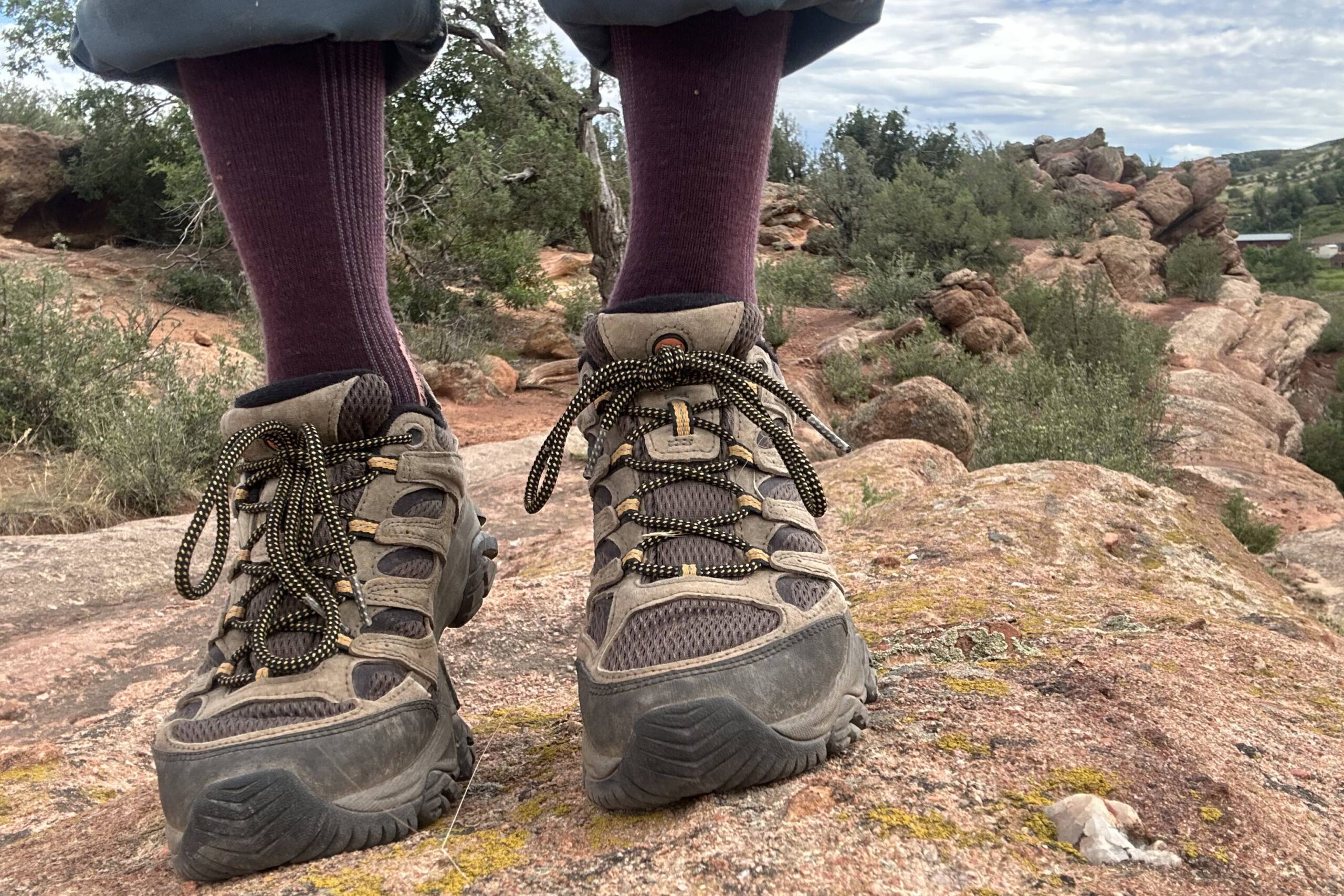 Close up shot of man wearing hiking shoes with red rocks and desert in background