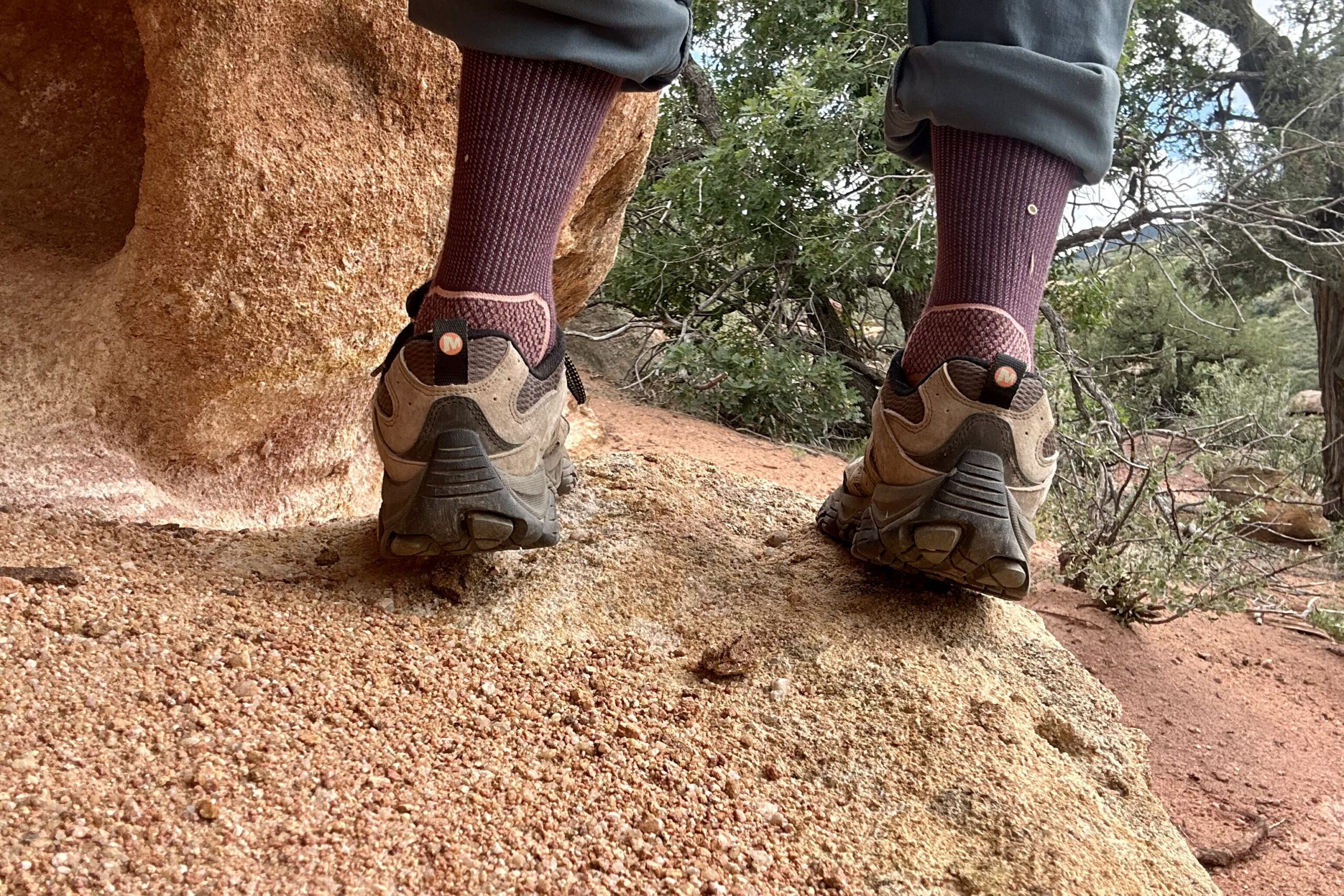 Man's legs from knee down shoes the back of the shoes with a sandy, red desert in background.