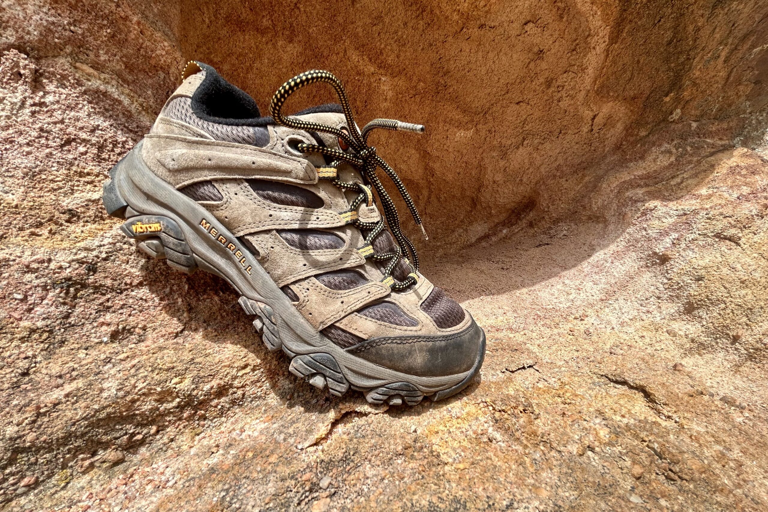 A single Merrell Moab 3 shoe is posed on a reddish rock.