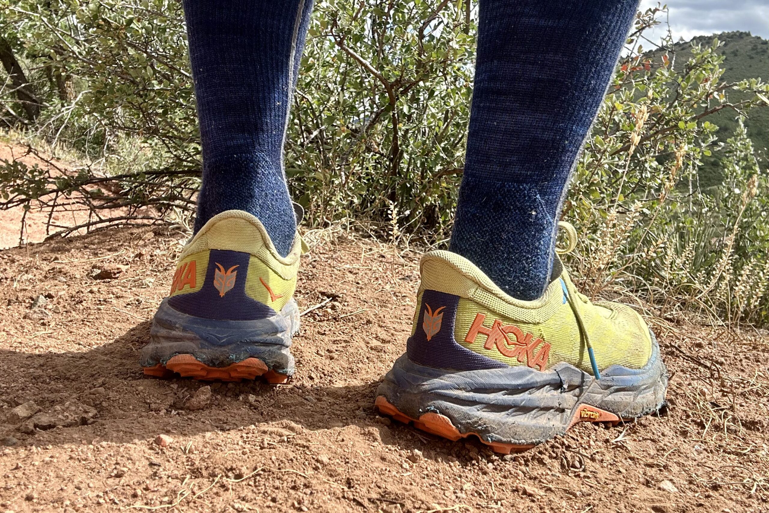 Closeup of trail running shoes from the knees down in a desert setting.