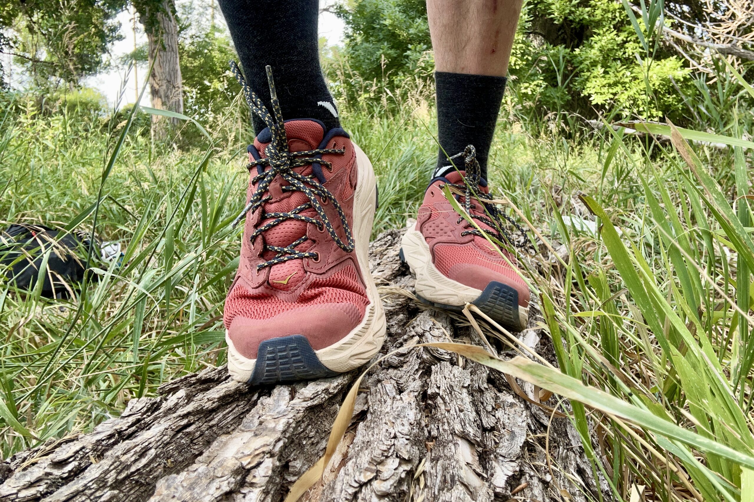 A closeup of a hiker wearing the HOKA Anacapa 2 Low while hiking across a log