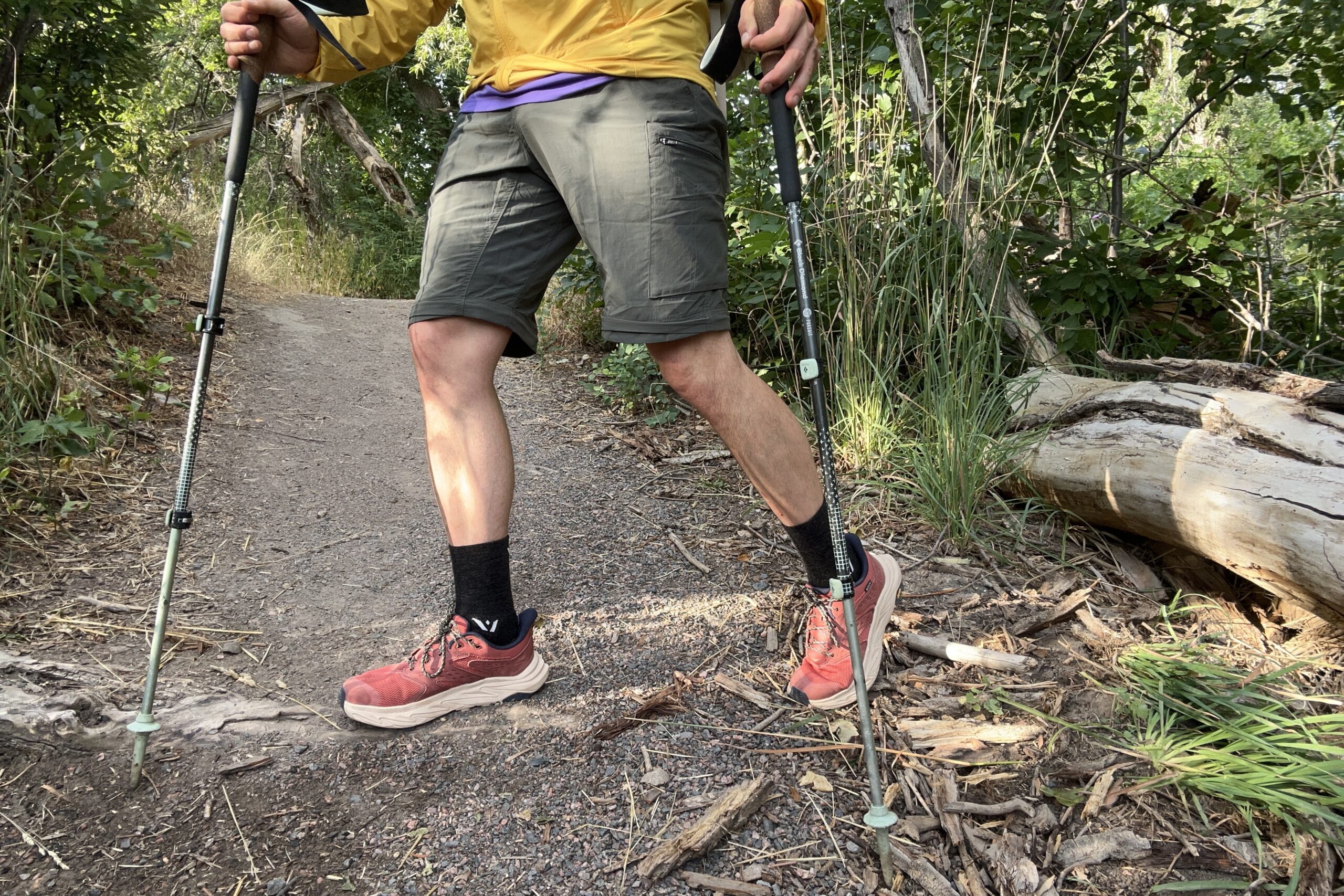 Uma foto de um homem da cintura para baixo, caminhando em uma trilha.