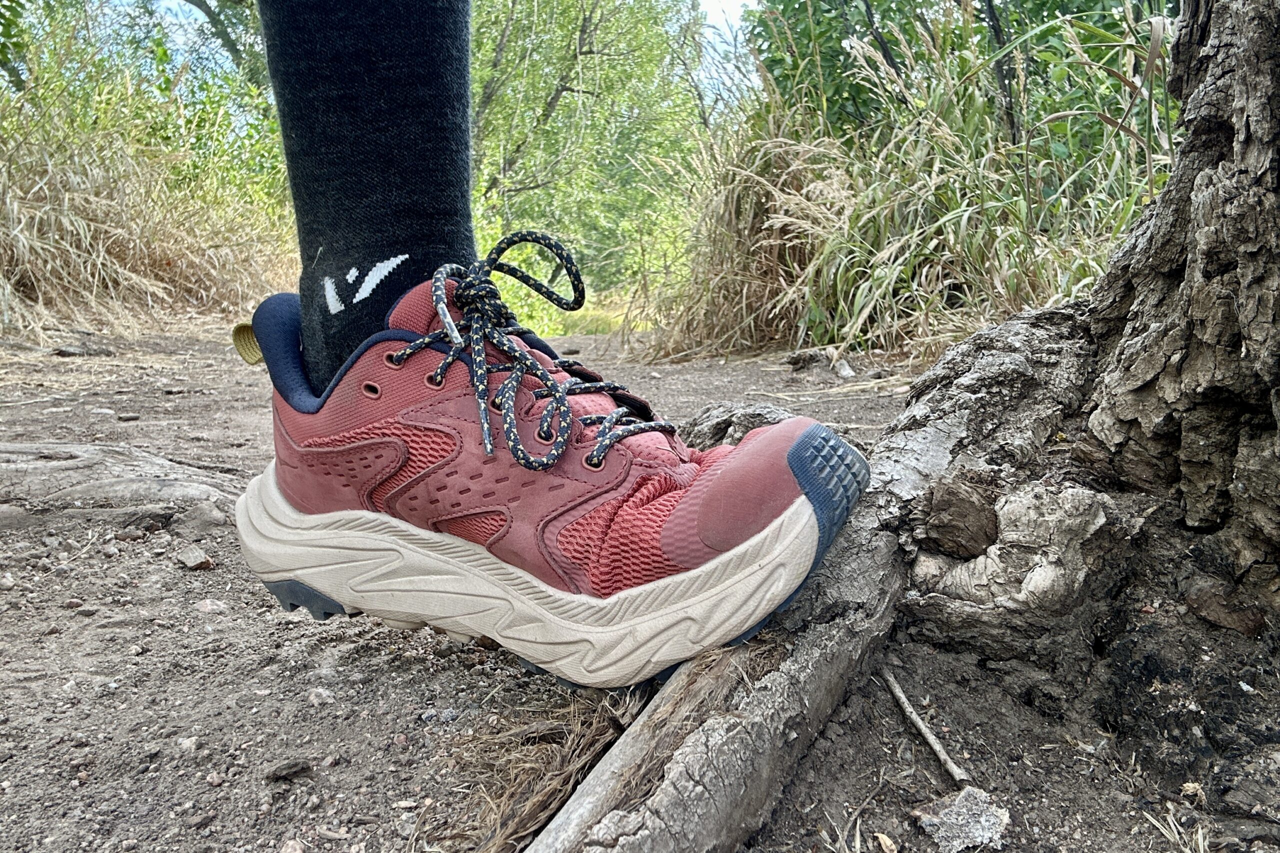 A closeup of the HOKA Anacapa 2 Low hiking shoes flexing against a tree root.