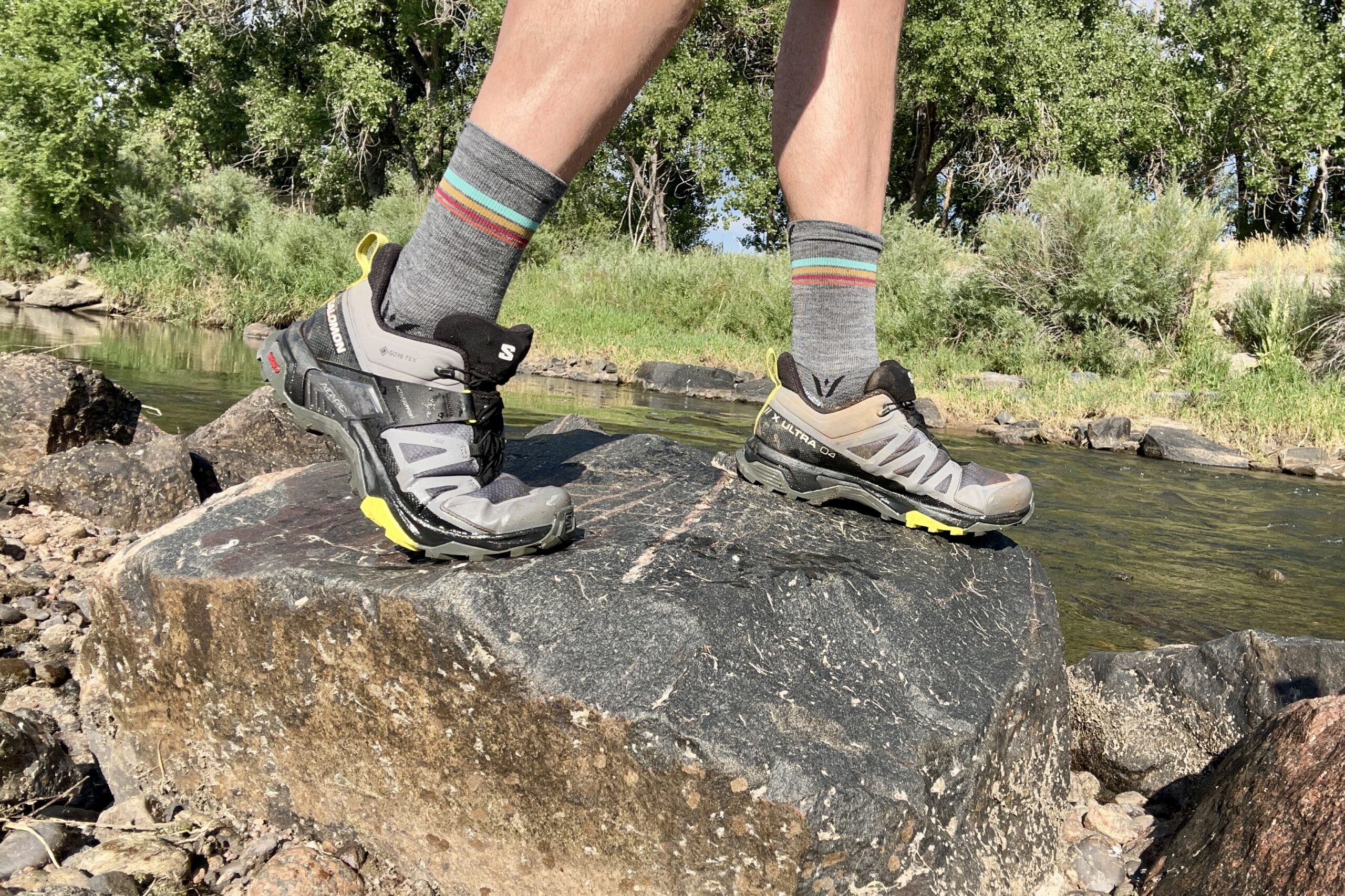 A close up shot of a man standing on a rock in the Salomon Ultra GTX 4 hiking shoes.