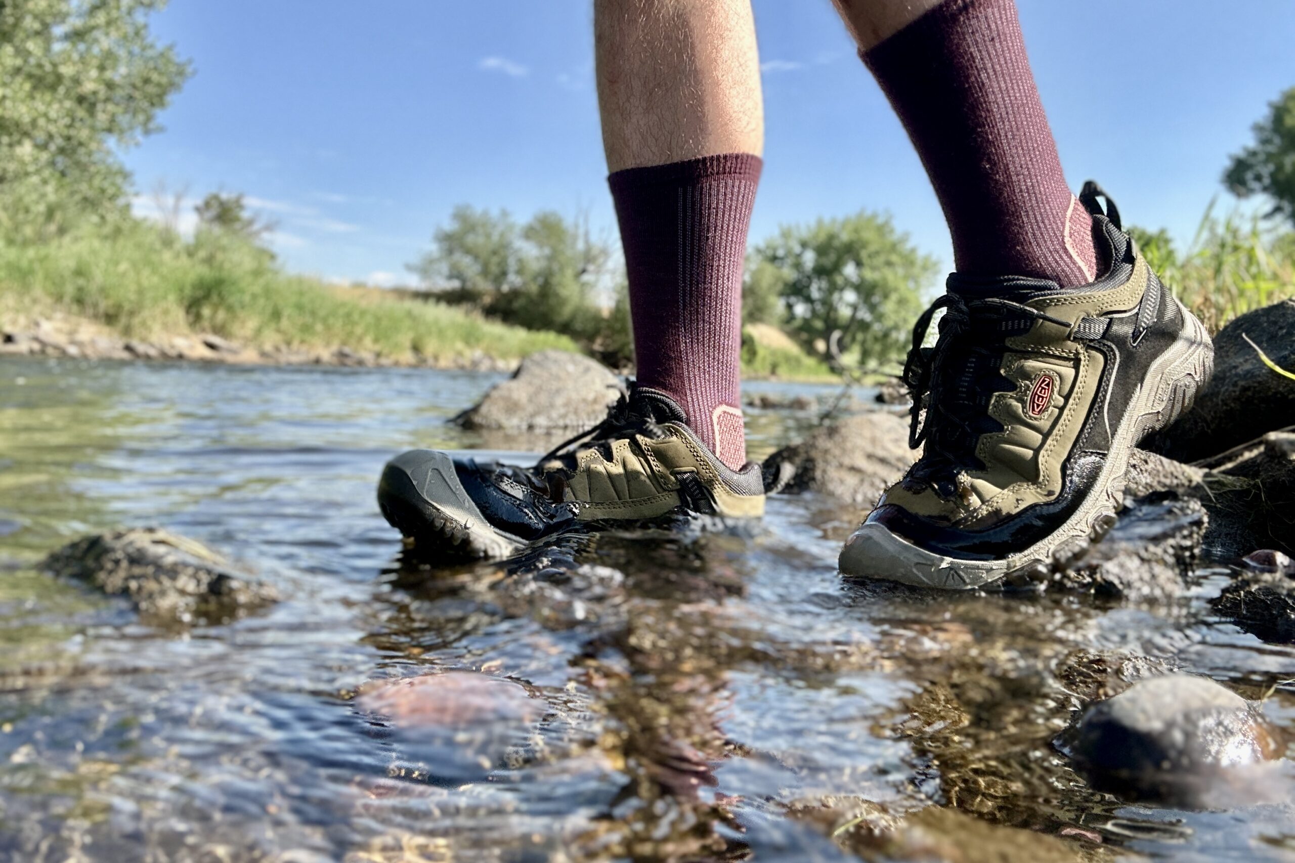 Uma visão de perto dos calçados de caminhada Keen Targhee IV, de lado, parcialmente submersos na água.