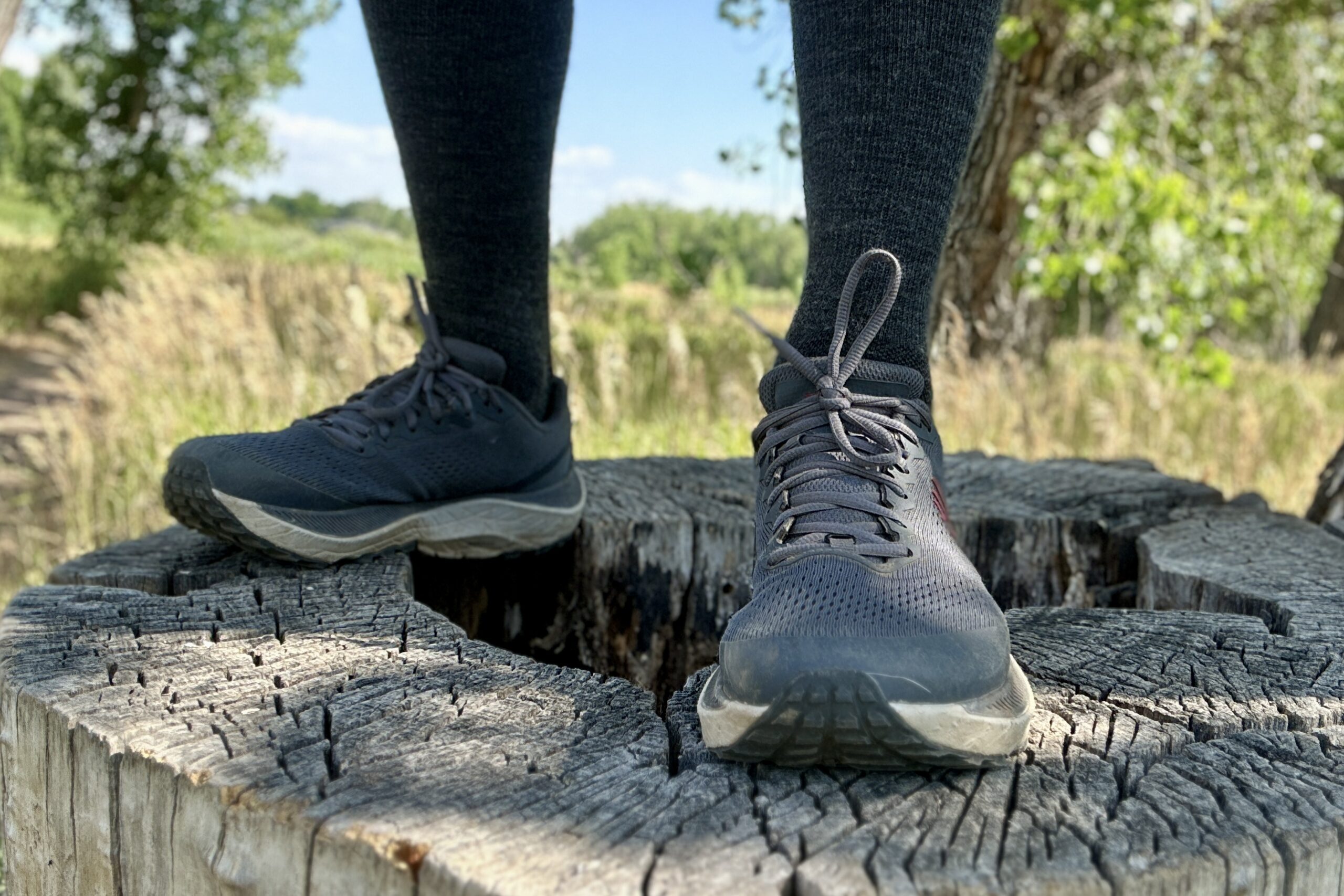 A hiker pauses to stand on a nearby stump while hiking.