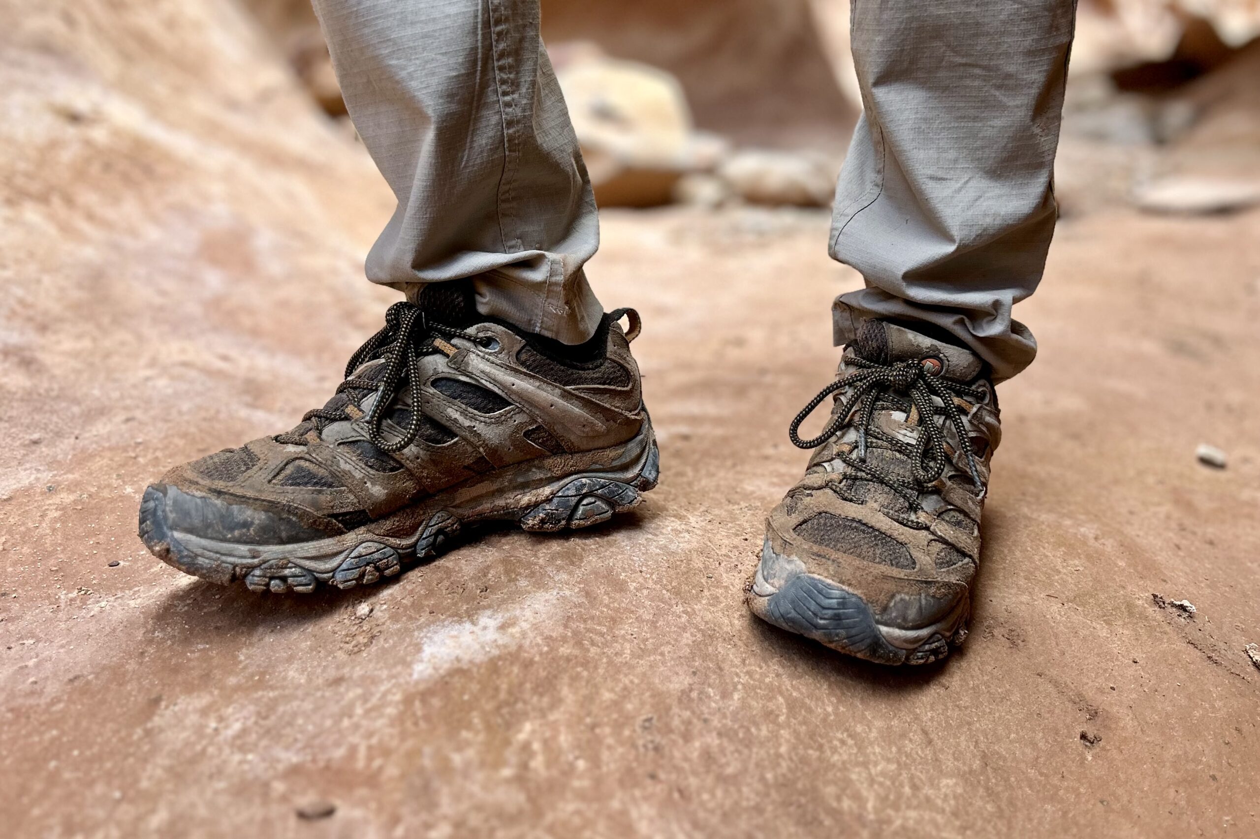 This is a picture of a man's legs from knee down wearing Merrell Moabs and tan pants in a slot canyon in Utah.