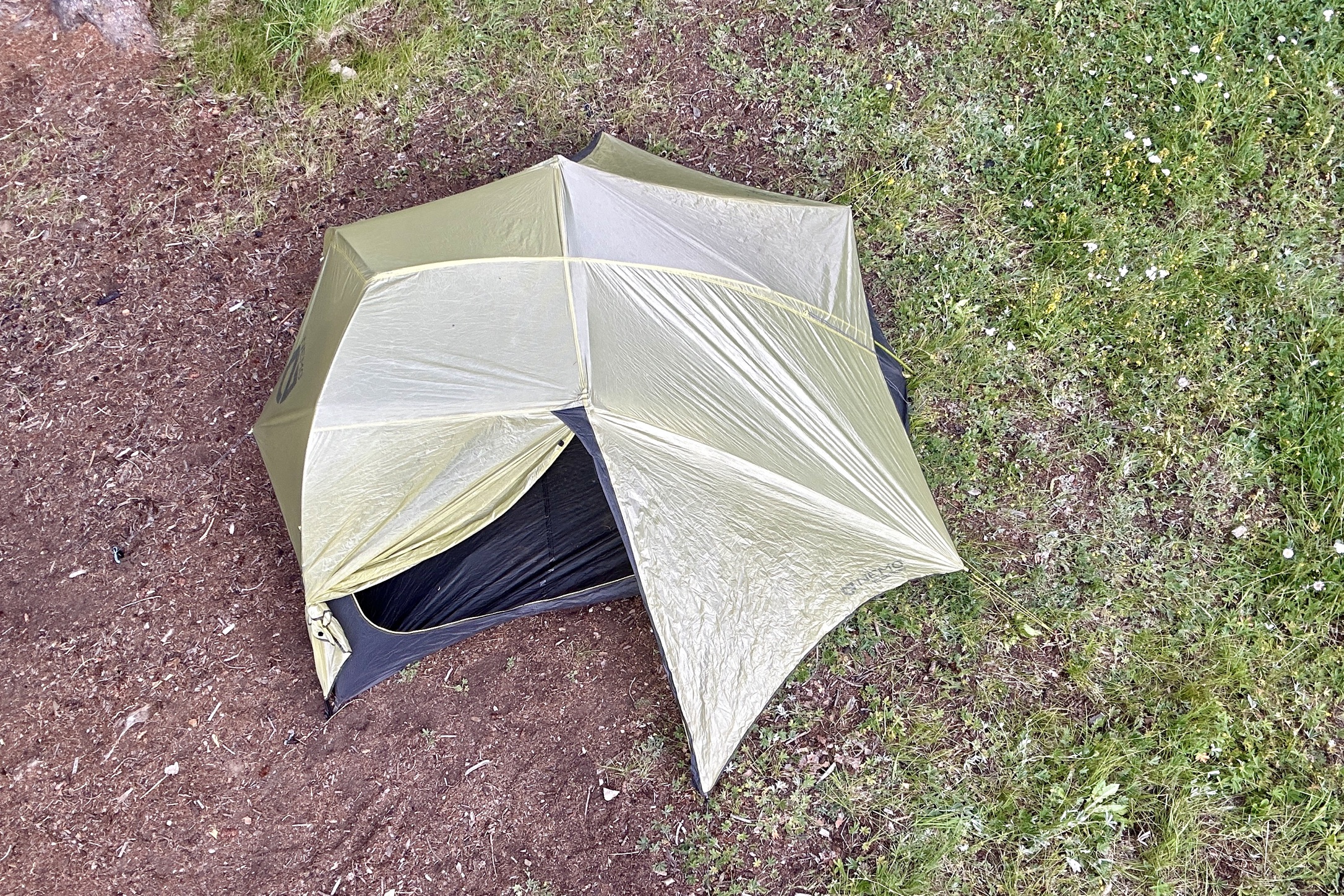 A top-down picture of a tent with both rainfly doors open in a forest so you can see the shape of it from above.