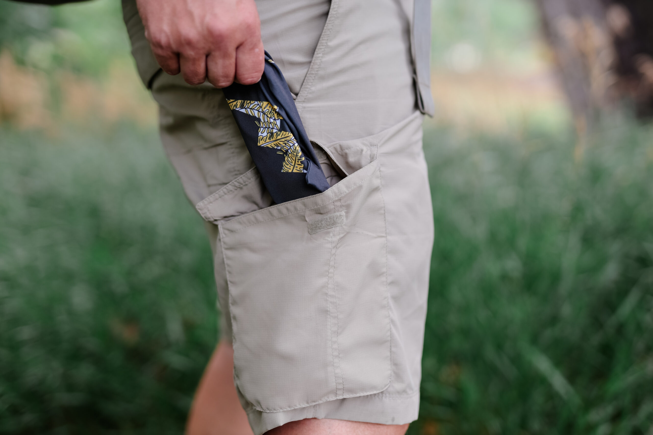 A hand grabbing sunglasses from the side pocket on a pair of shorts