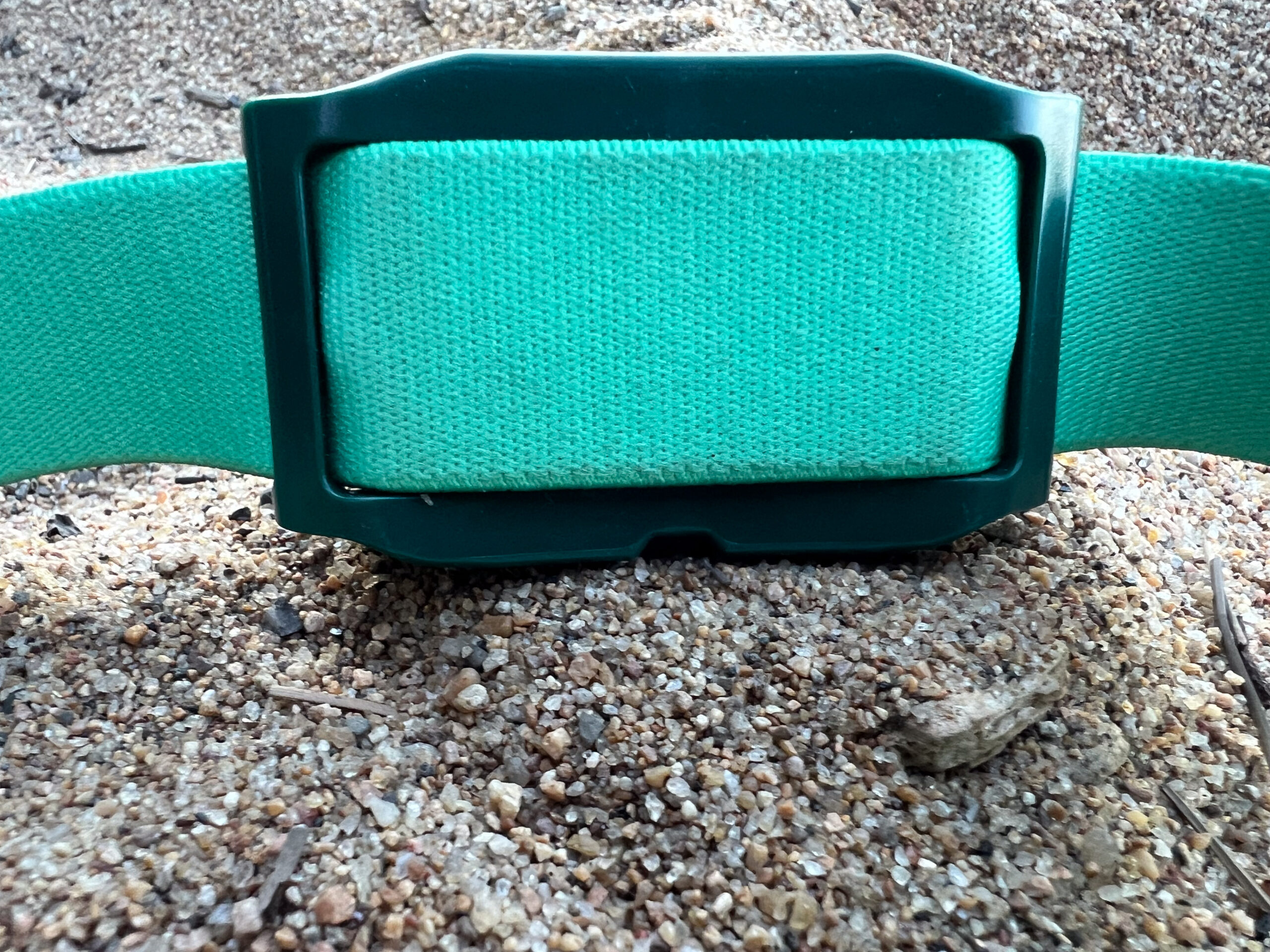 The image shows the rear of the Petzl Tikkina headlamp body sitting in the sand.