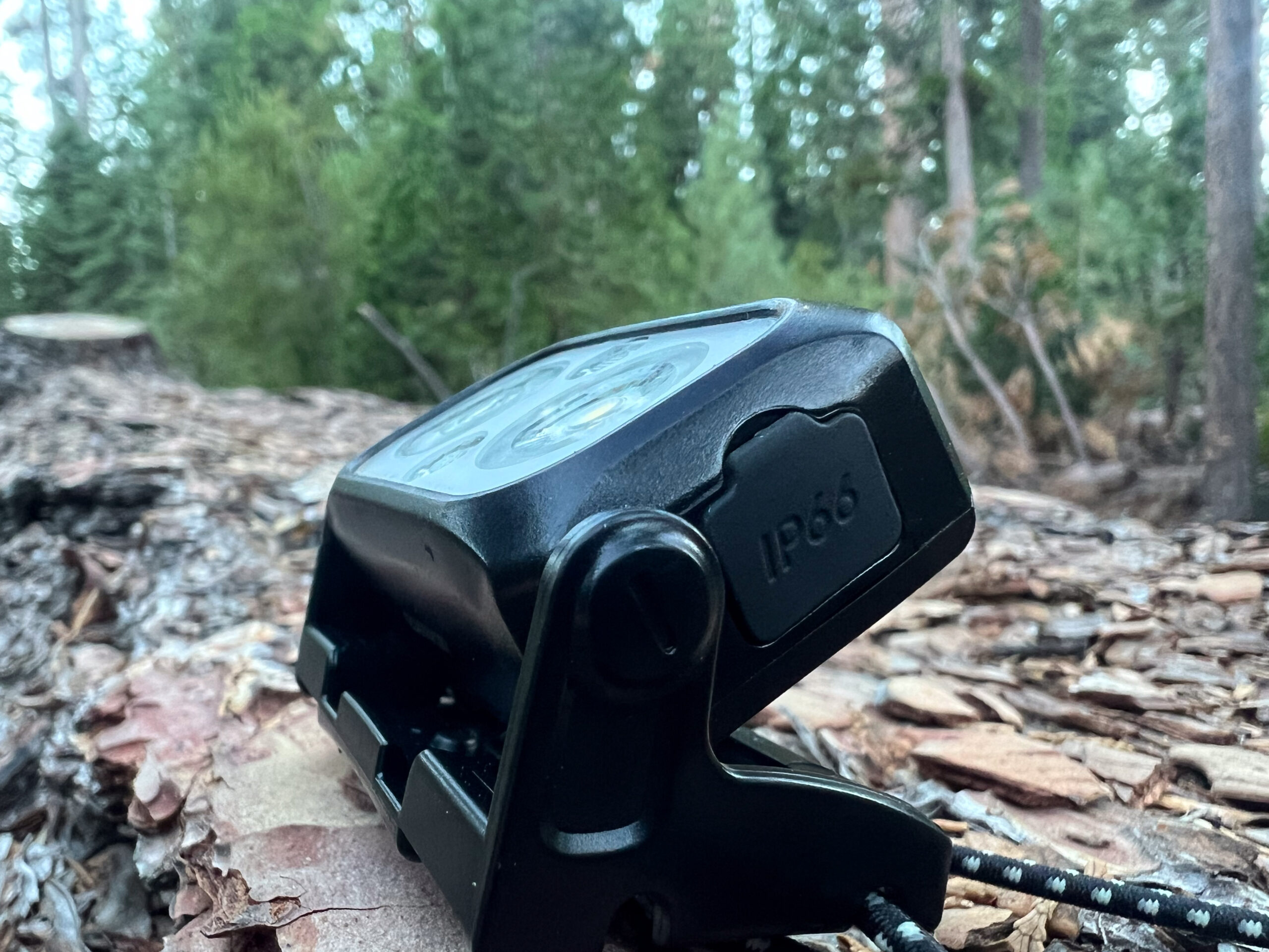 The image shows a headlamp tilted towards the sky. The headlamp is sitting on a downed log.