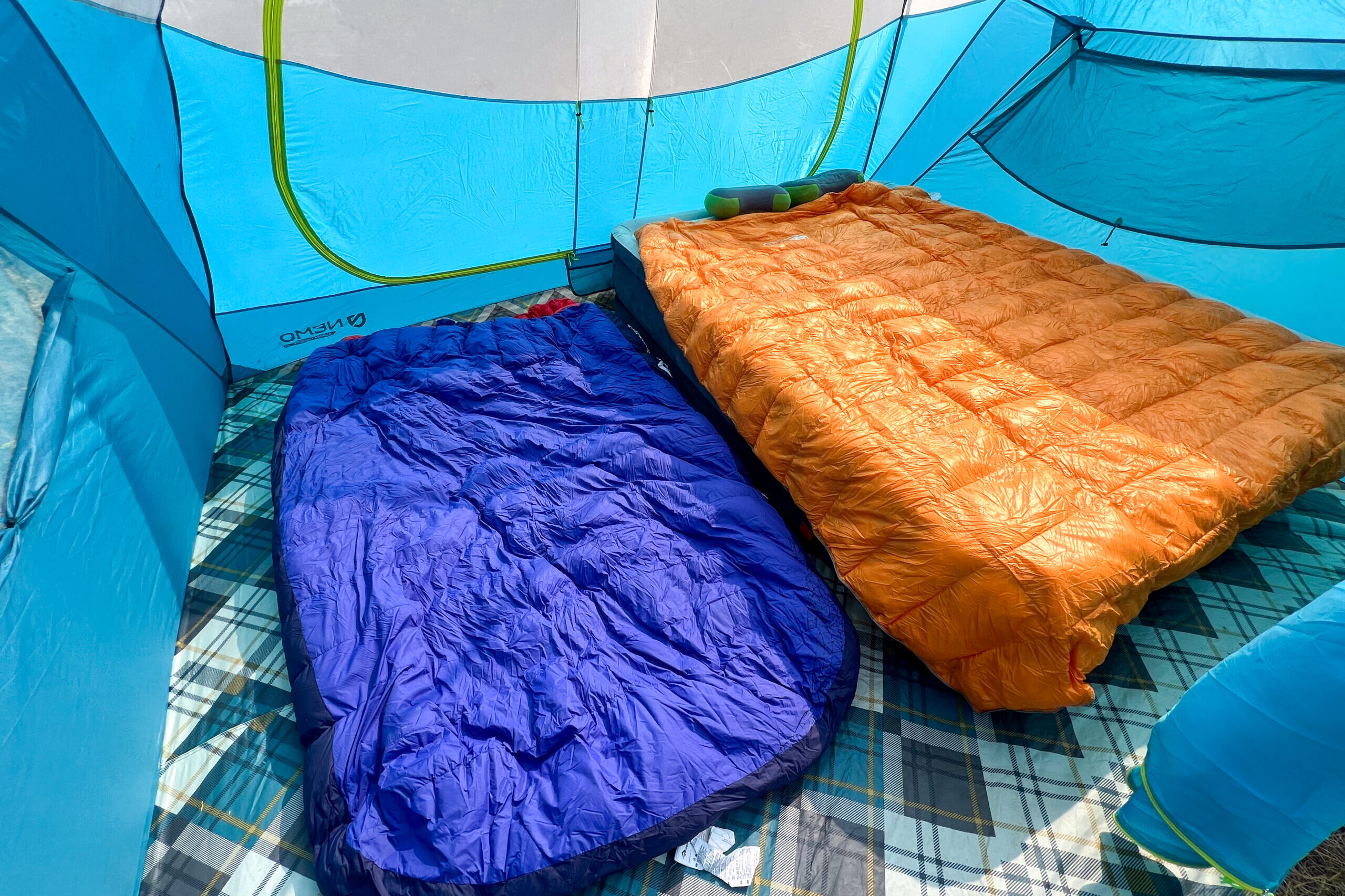 The image shows the interior of the Nemo Aurora Highrise 4 tent. Inside the tent there is a queen sized air mattress and a double sized sleeping bag.