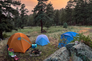 The image shows three tents in a filed set against a post-storm burnt orange sky.