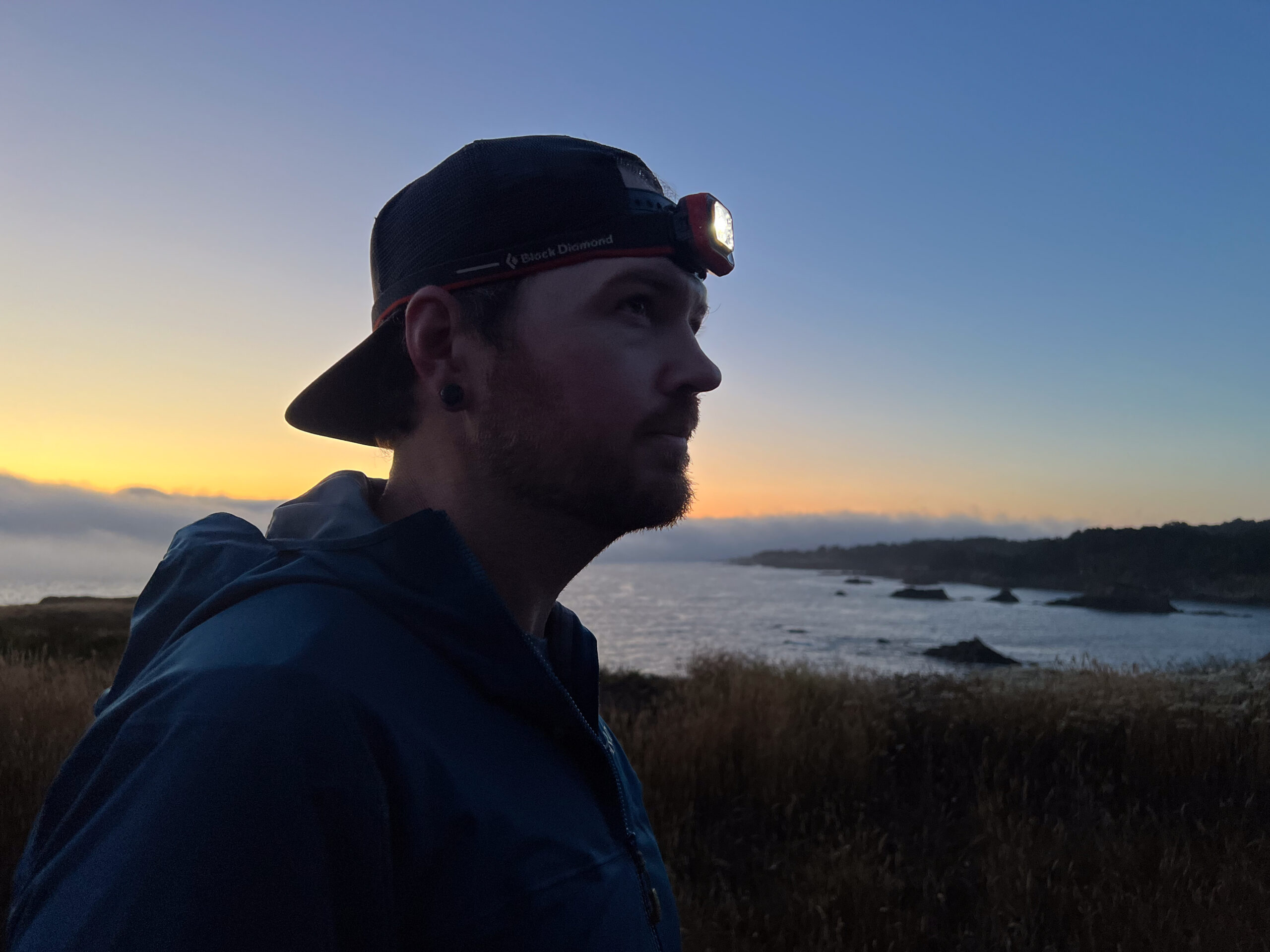 The image shows a runner wearing the Spot 400 set against the sun setting over the ocean.