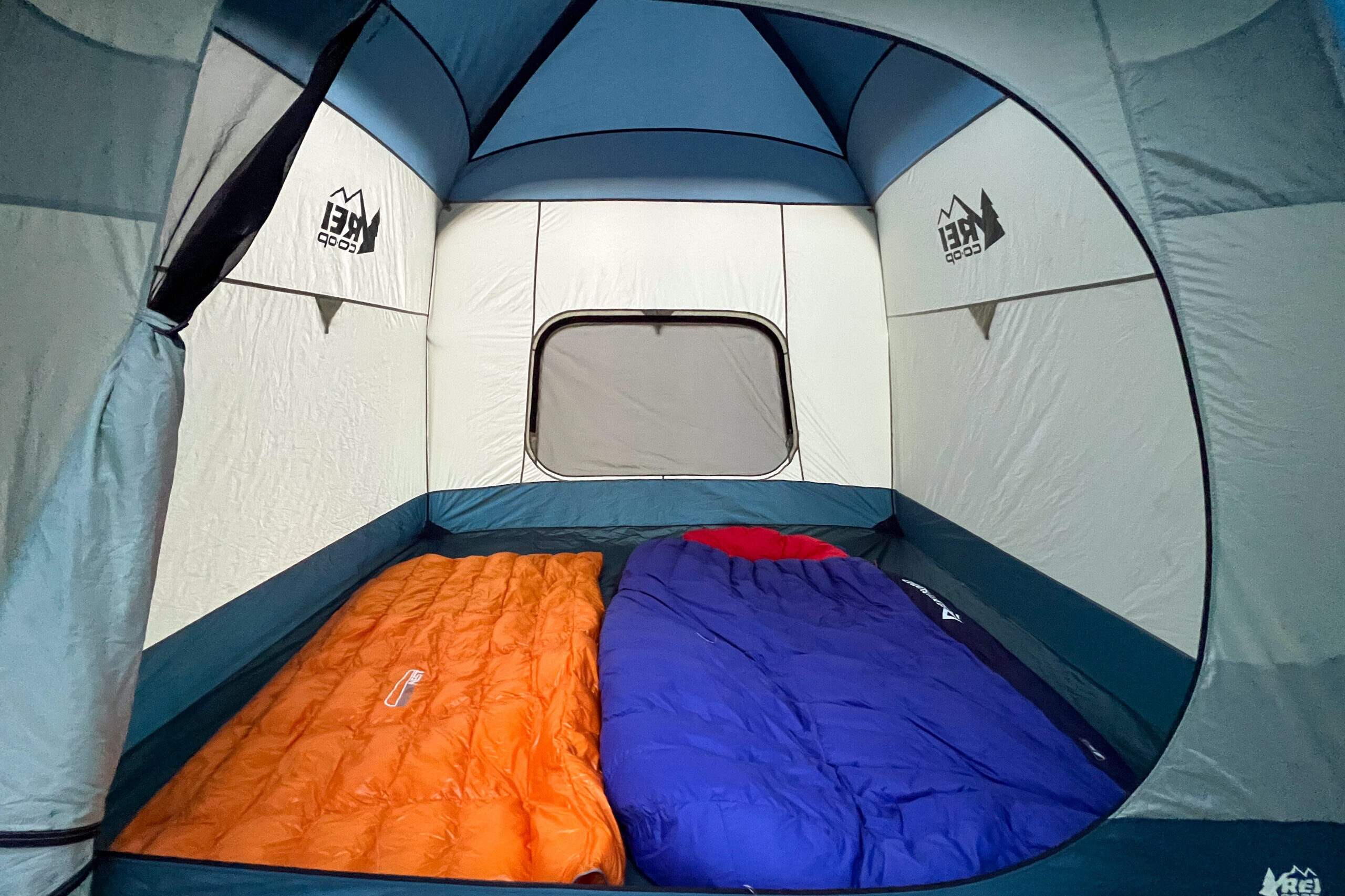 The image shows the interor of the REI Skyward 4 tent. The inside of the tent has a double sized sleeping bag and a single sleeping bag to show the interior of the tent.