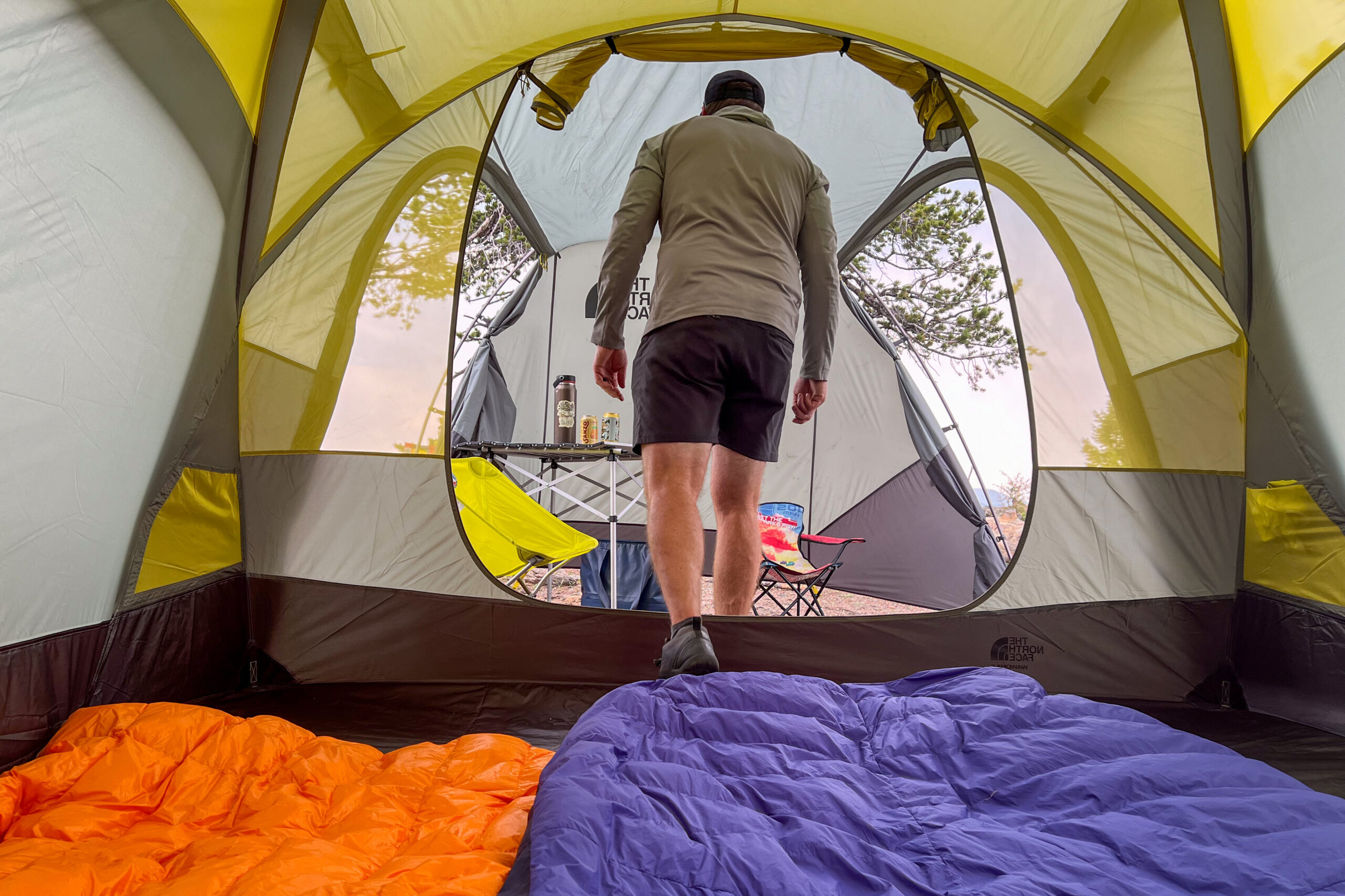 The image shows a camper exiting The North Face Wawona 6 tent. The image was taken from inside the ten and is looking out toward the front vestibule.