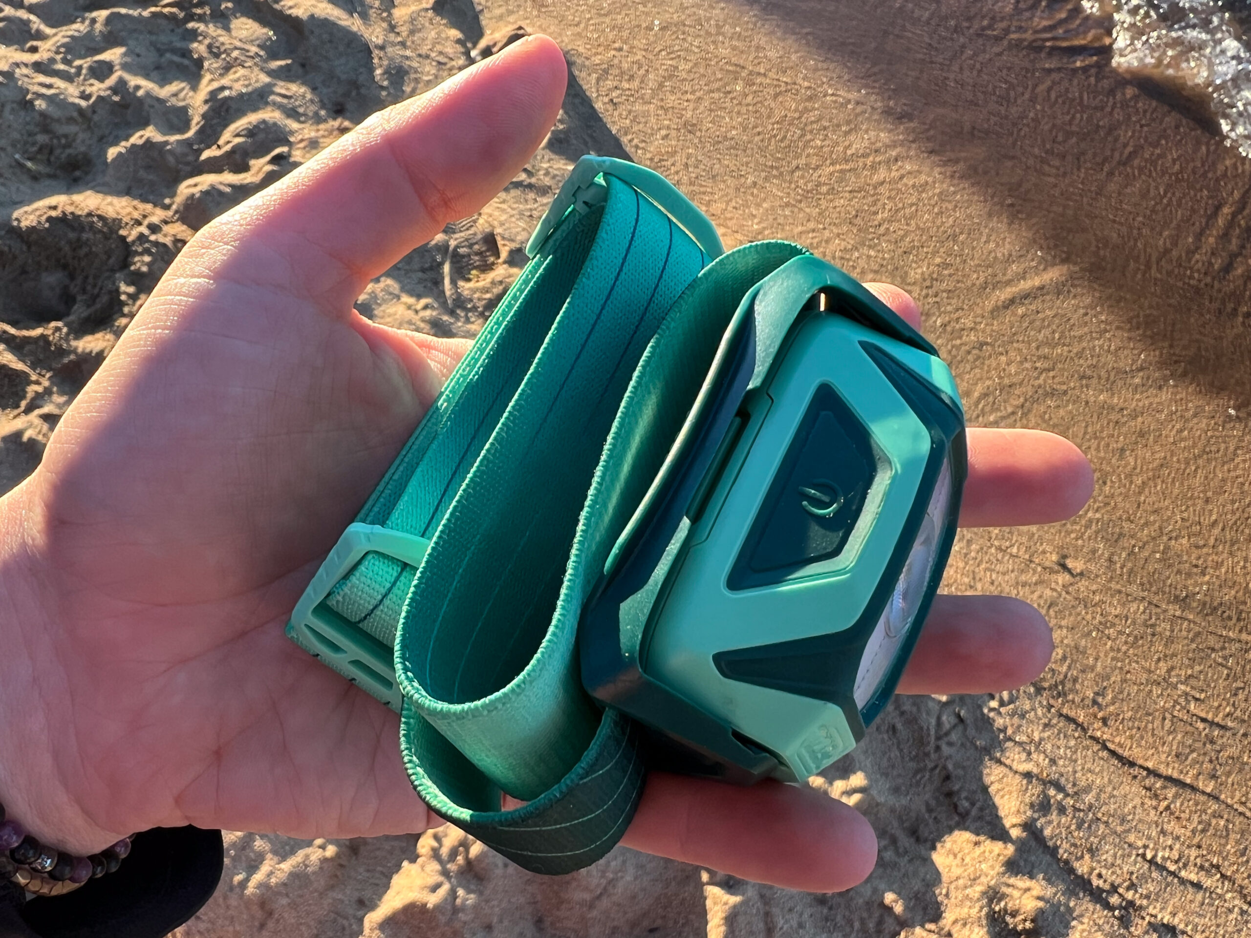 a camper on the beach holding their petzl tikkina