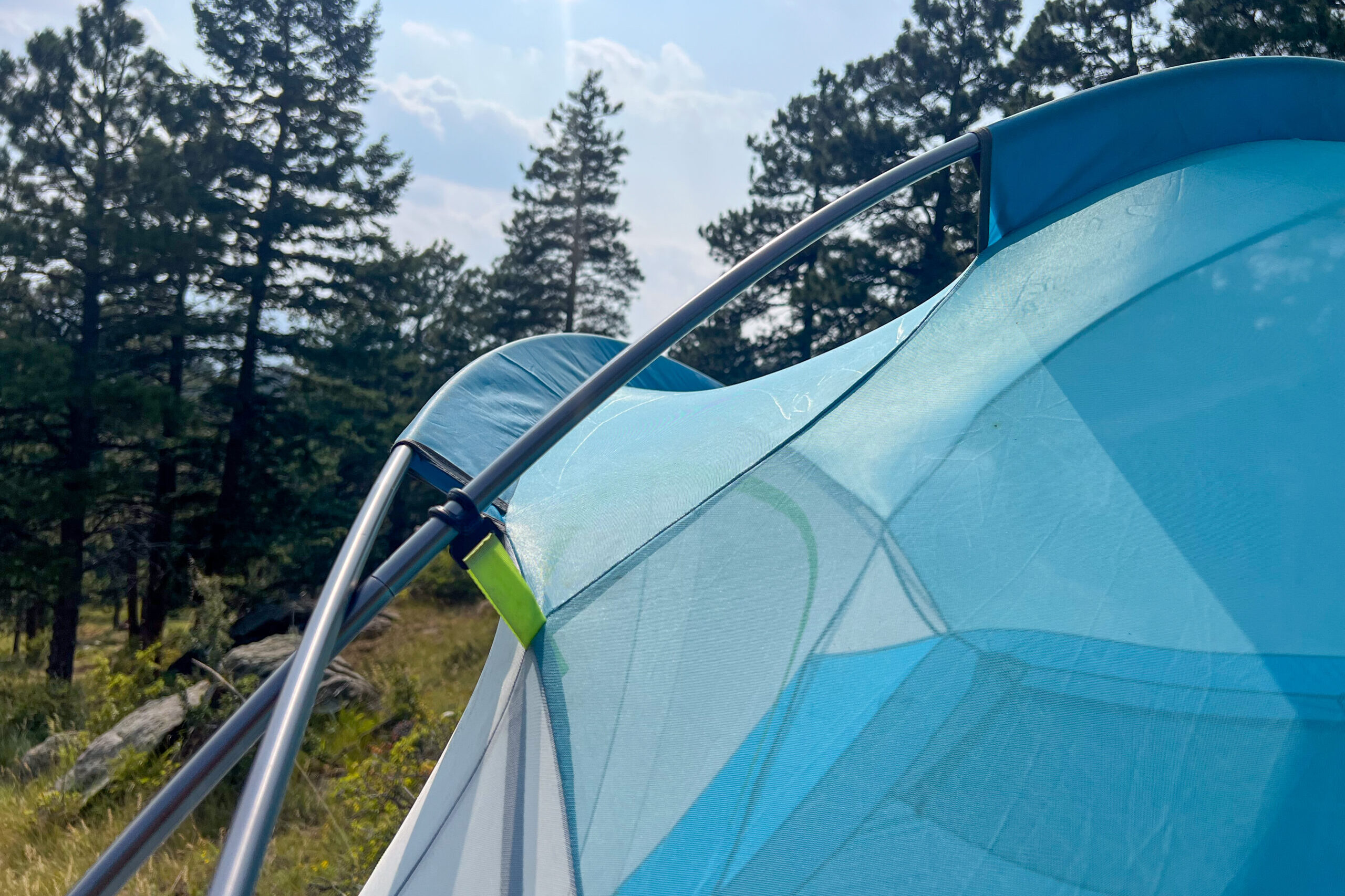 The image shows two tent poles crossing over each other on the left with the mesh tent upper on the right.