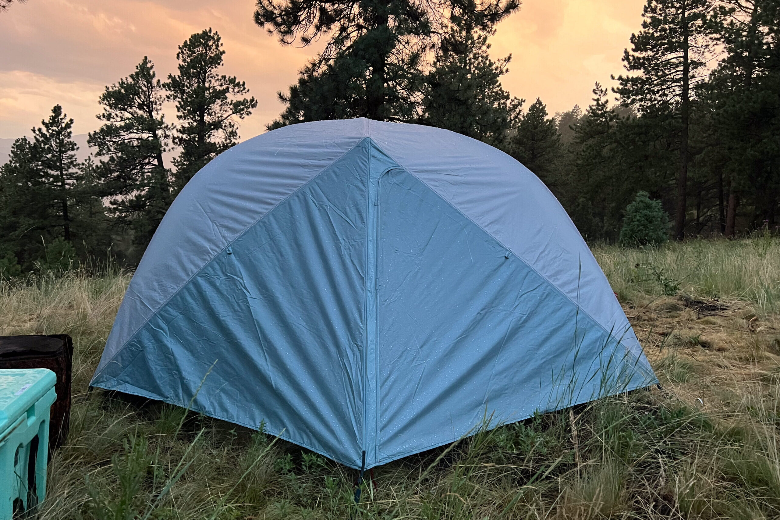 The image shows the front of the Mountain Hardware Mineral King 3 set against the sunset after a rainstorm. The sky is a burnt orange.