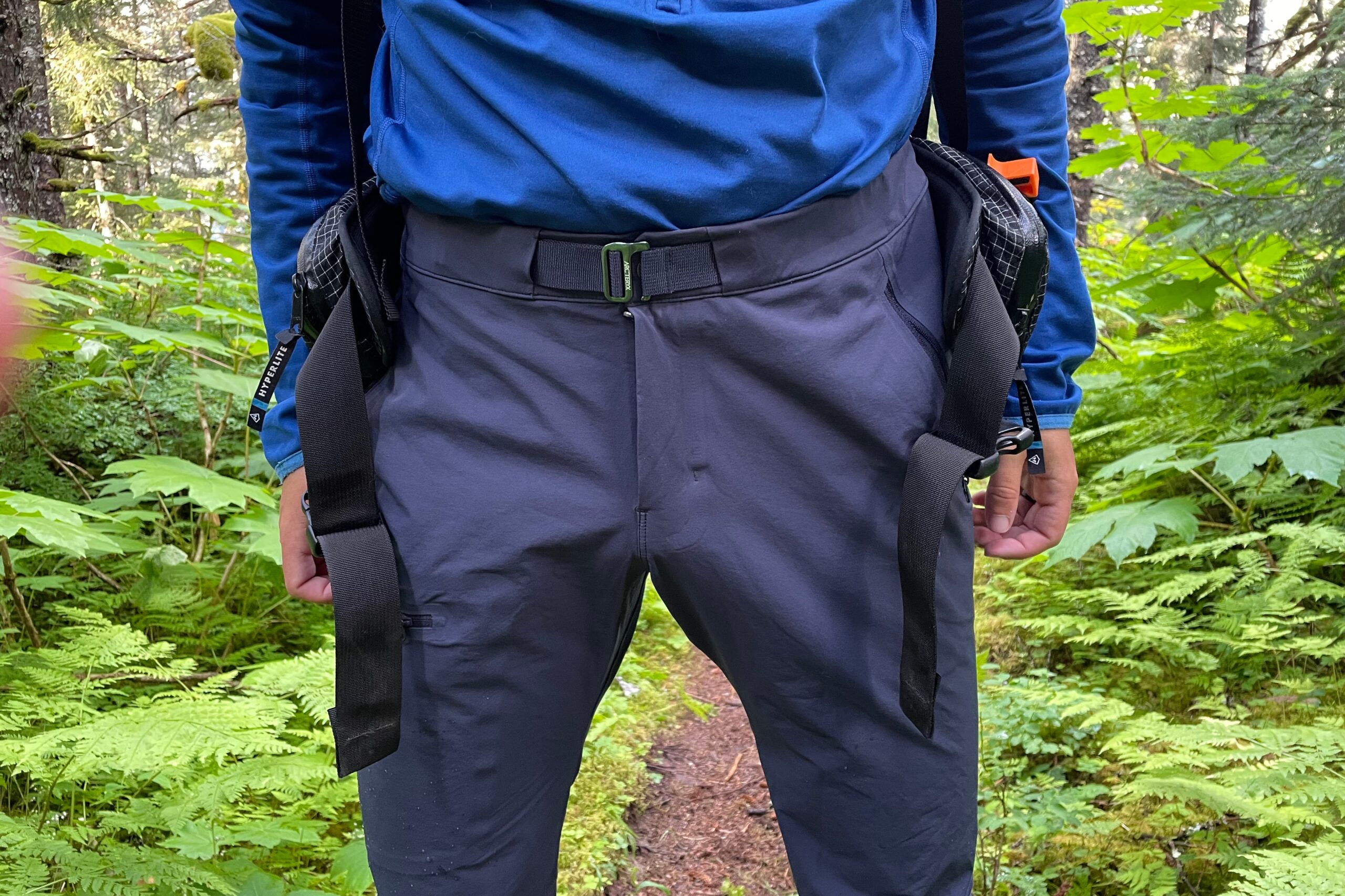 Um close da cintura de uma calça de caminhada em um cenário de floresta.