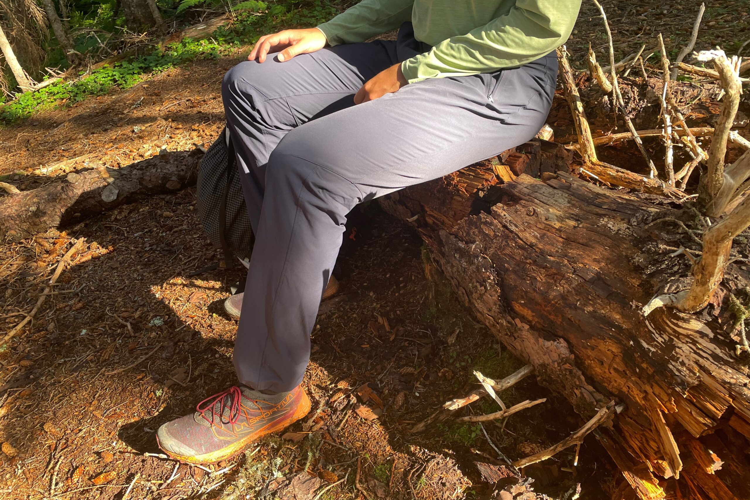 A man sits on a long on a hiking trail.