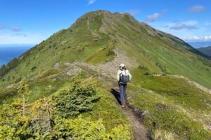 A man walks on an alpine ridge in the sunshine.