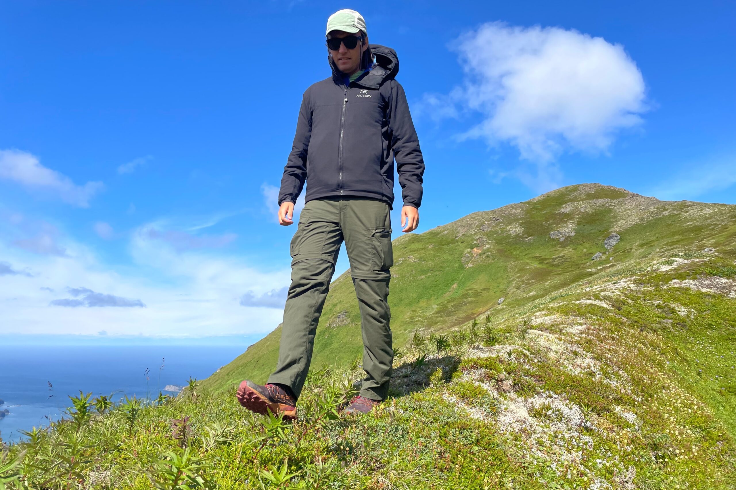 A full body shot of a man walking down an alpine ridge.