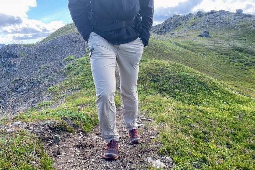 A man walks toward the camera on an alpine trail