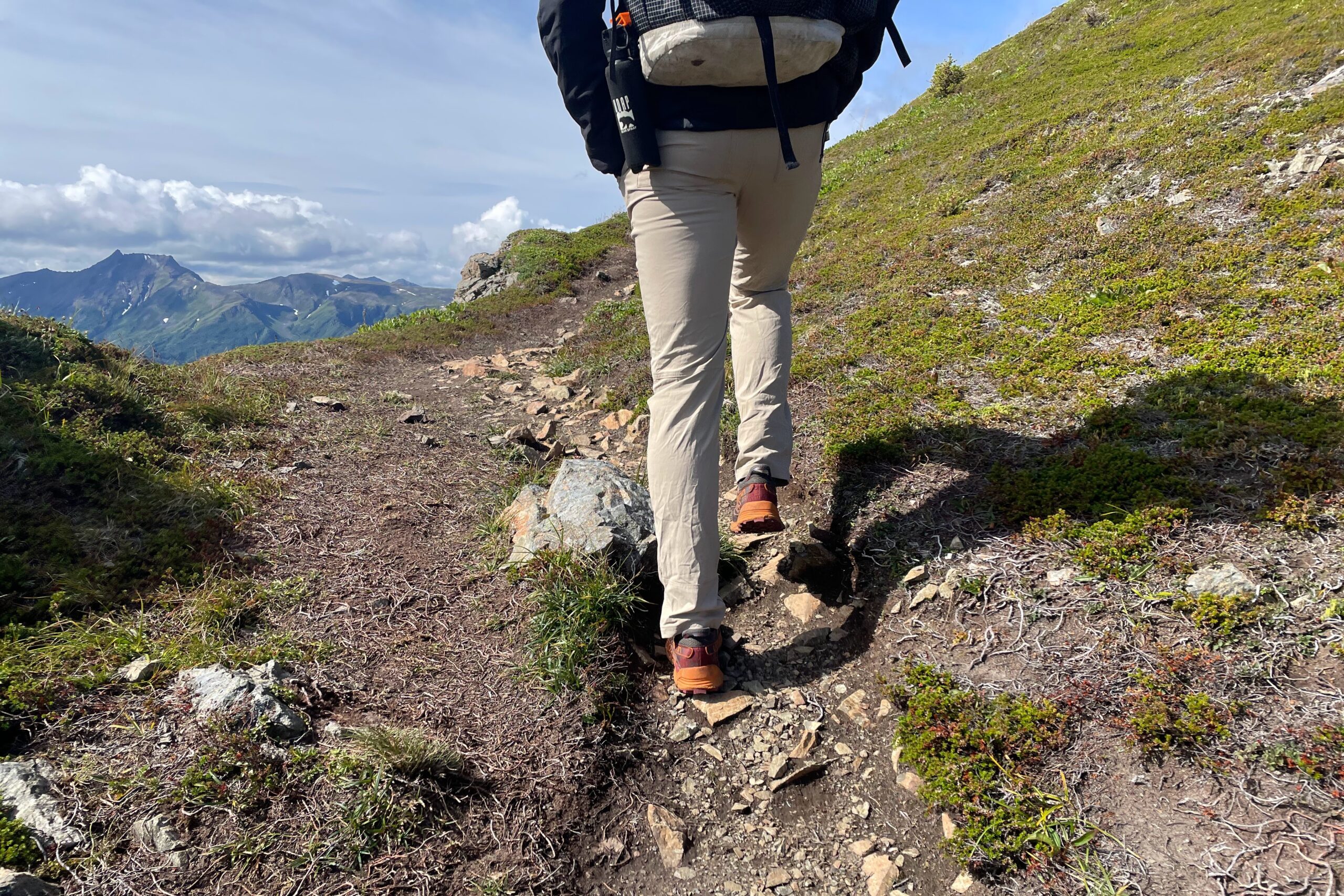 A man walks away from the camera on an alpine trail.