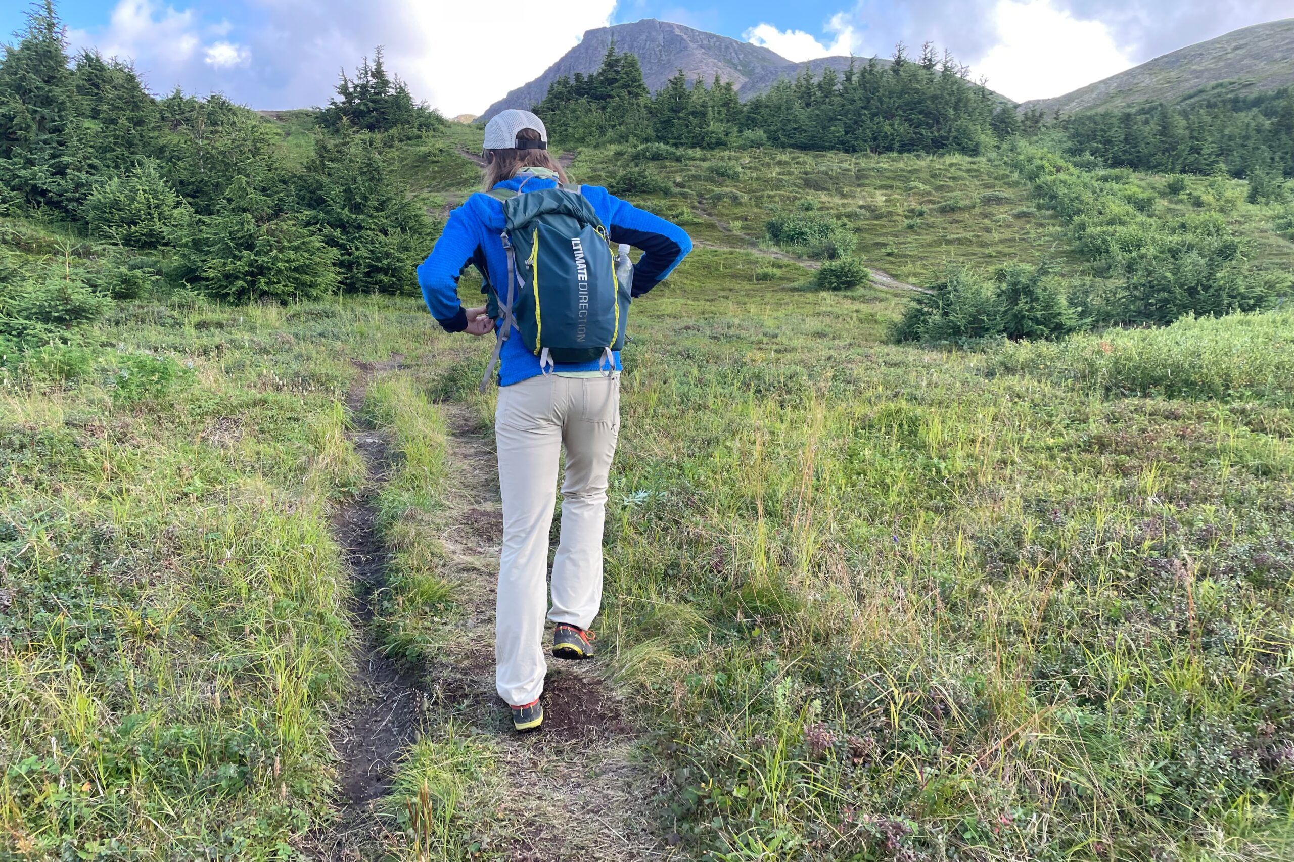 A man walks uphill on an alpine trail.