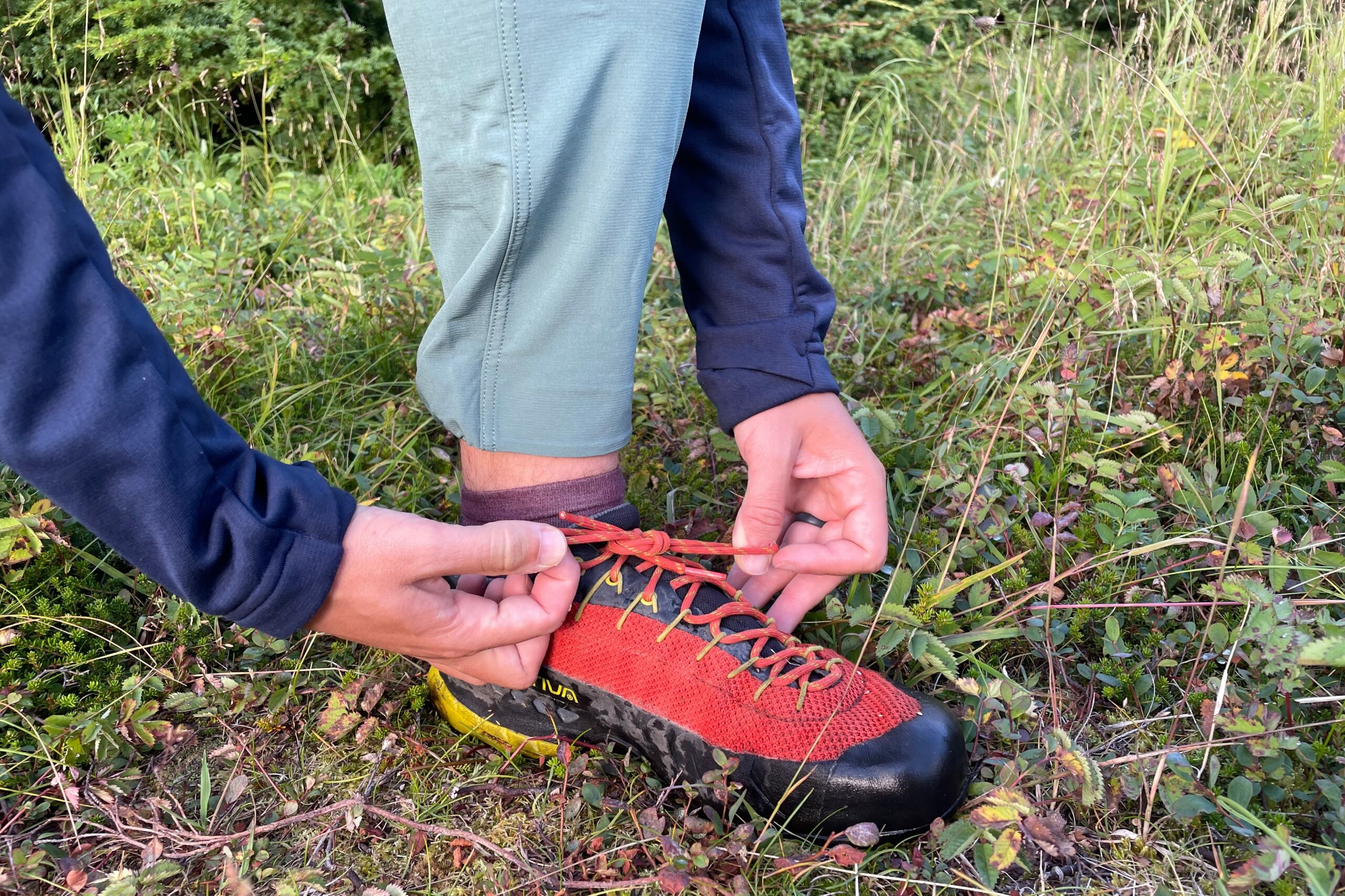 A man ties his shoes in the tundra.