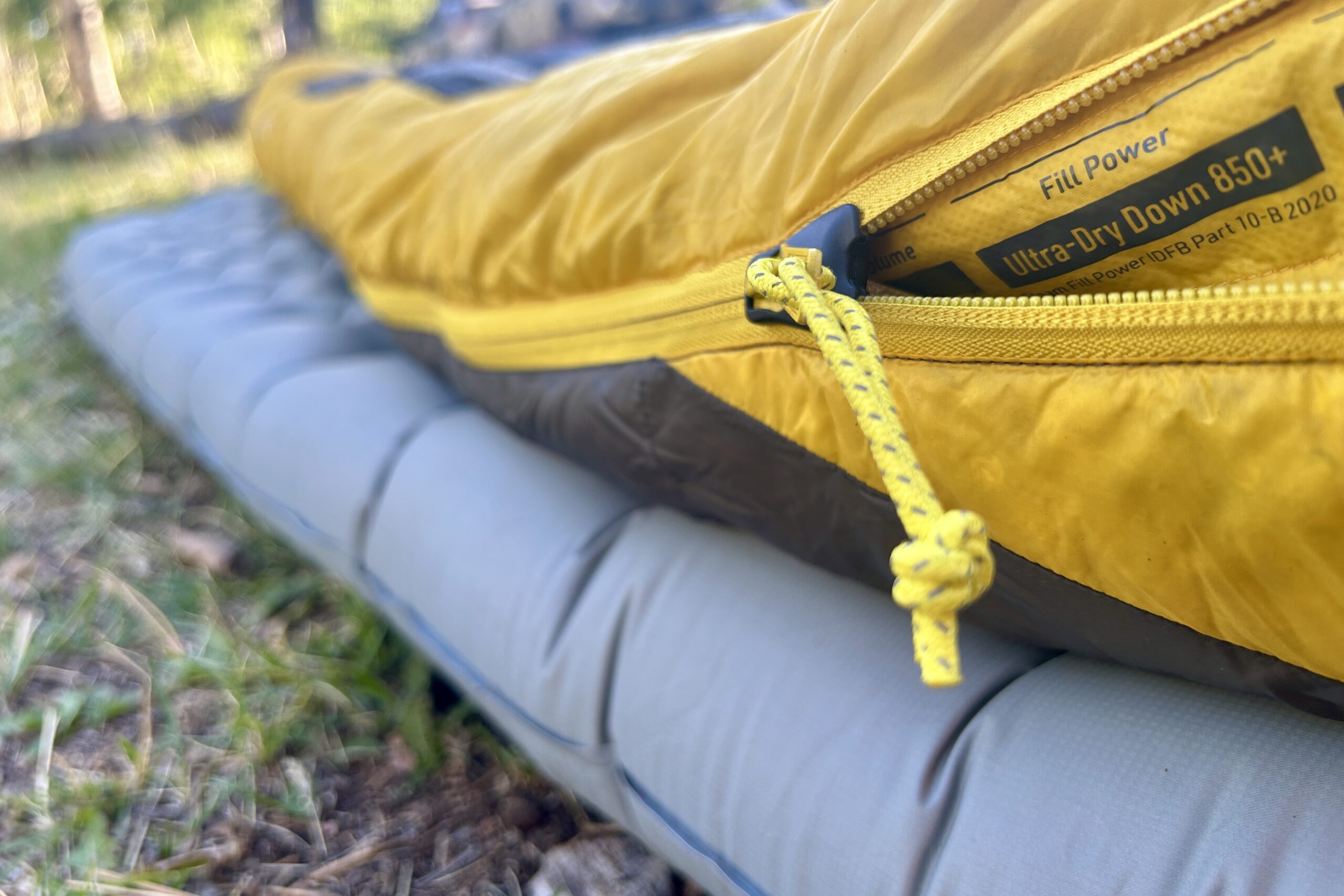 A close-up image of a sleeping bag from the side with a long zipper tab.