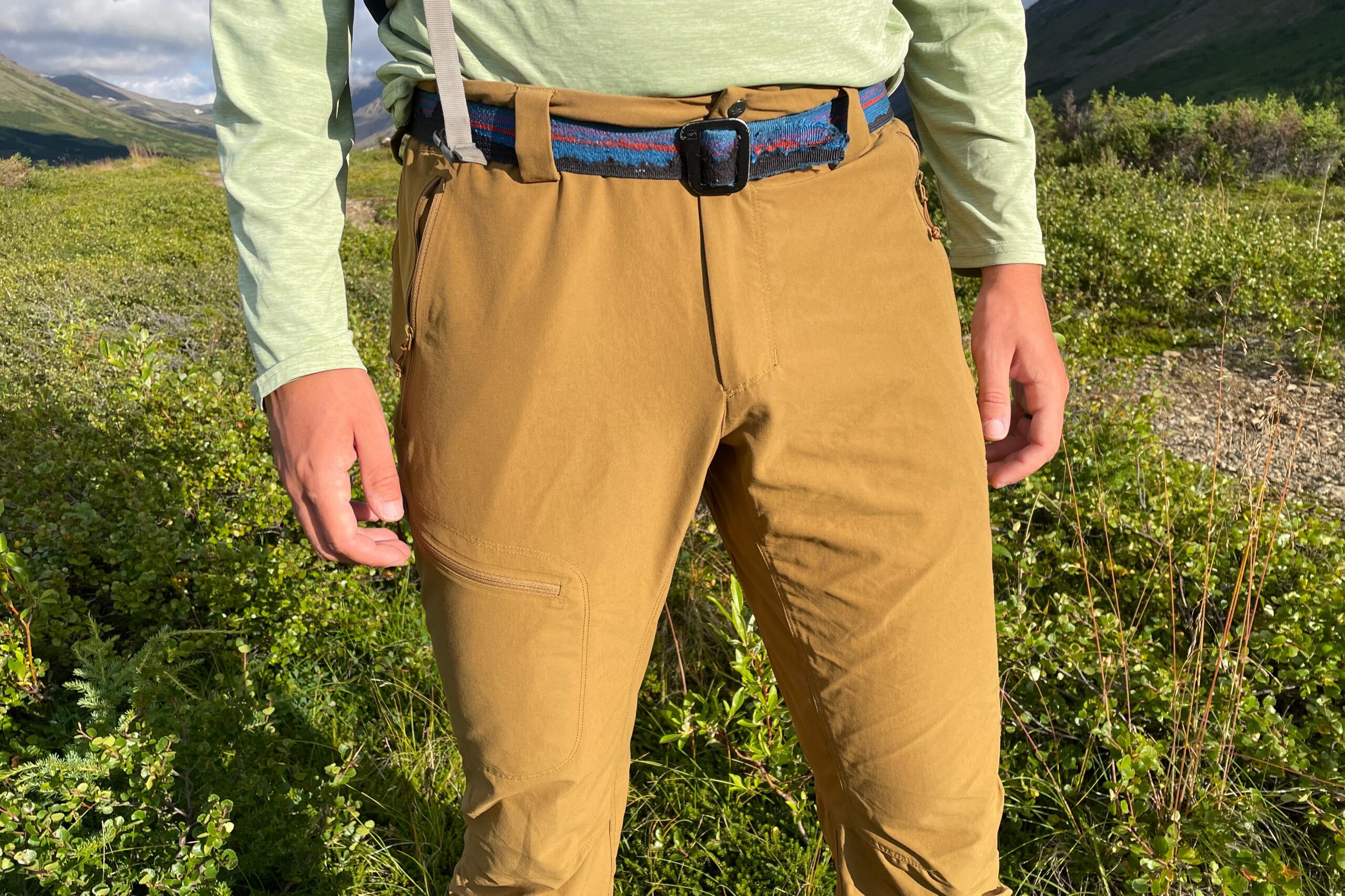 A closeup of the waist of a man standing in the alpine.