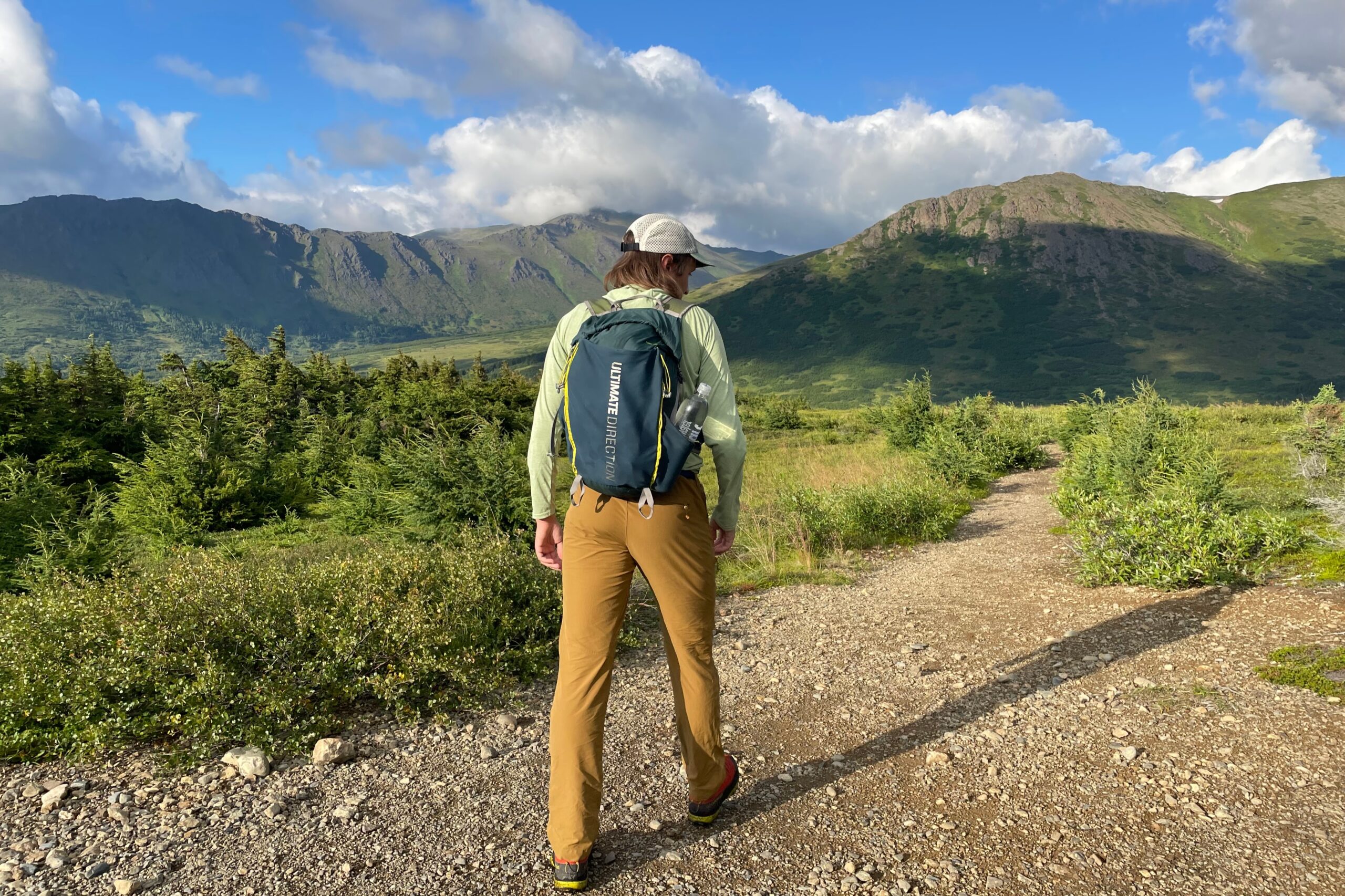 A man walks away from the camera on an alpine trail.