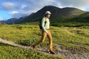 A man walks on an alpine trail in the sunshine.