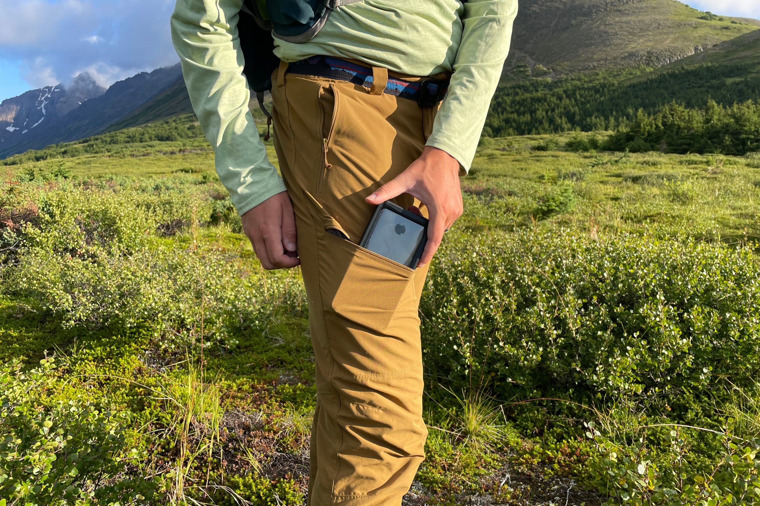 A man places a phone in a zippered thigh pocket.