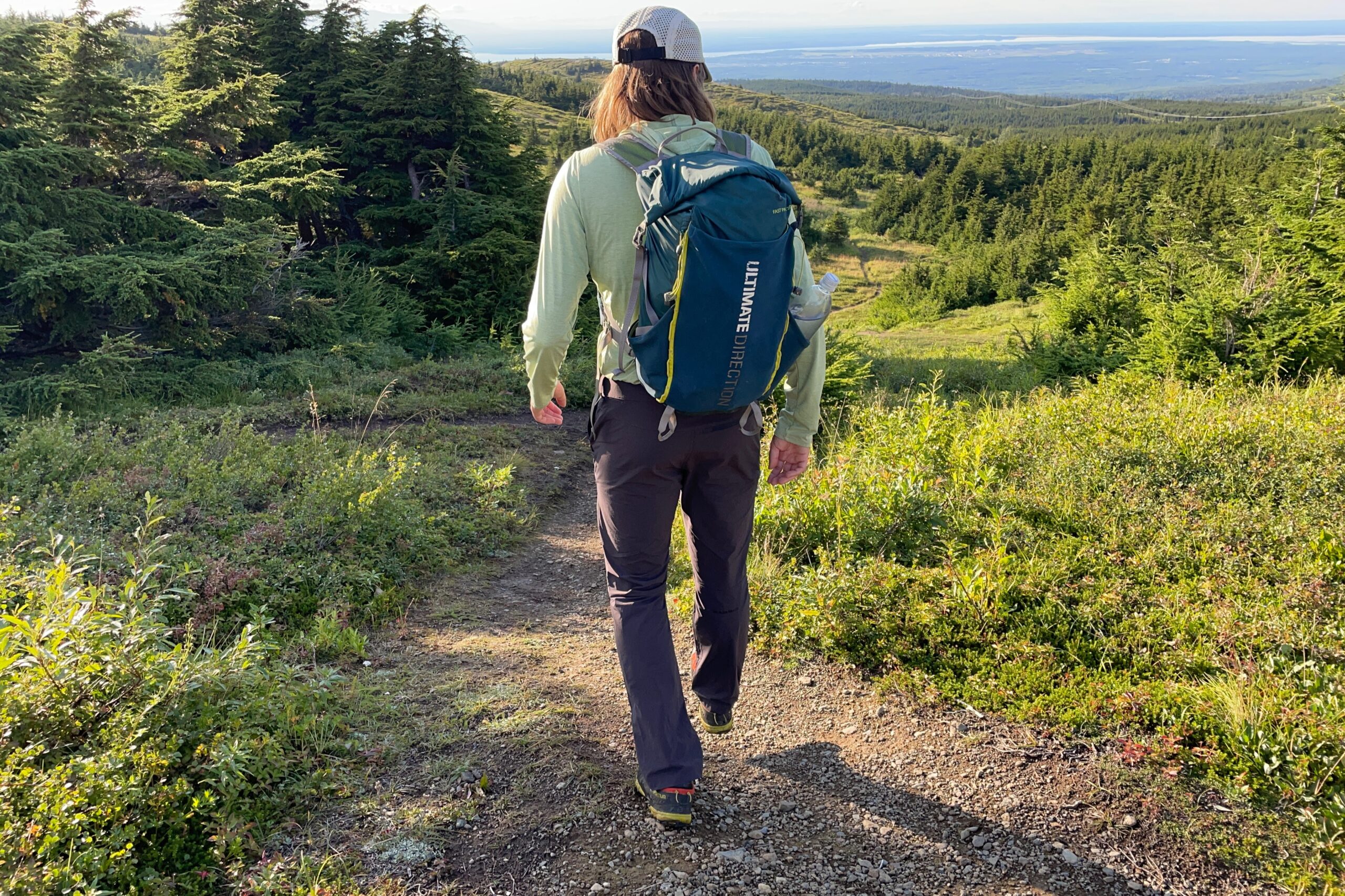 A man walks down a hill at sunset.