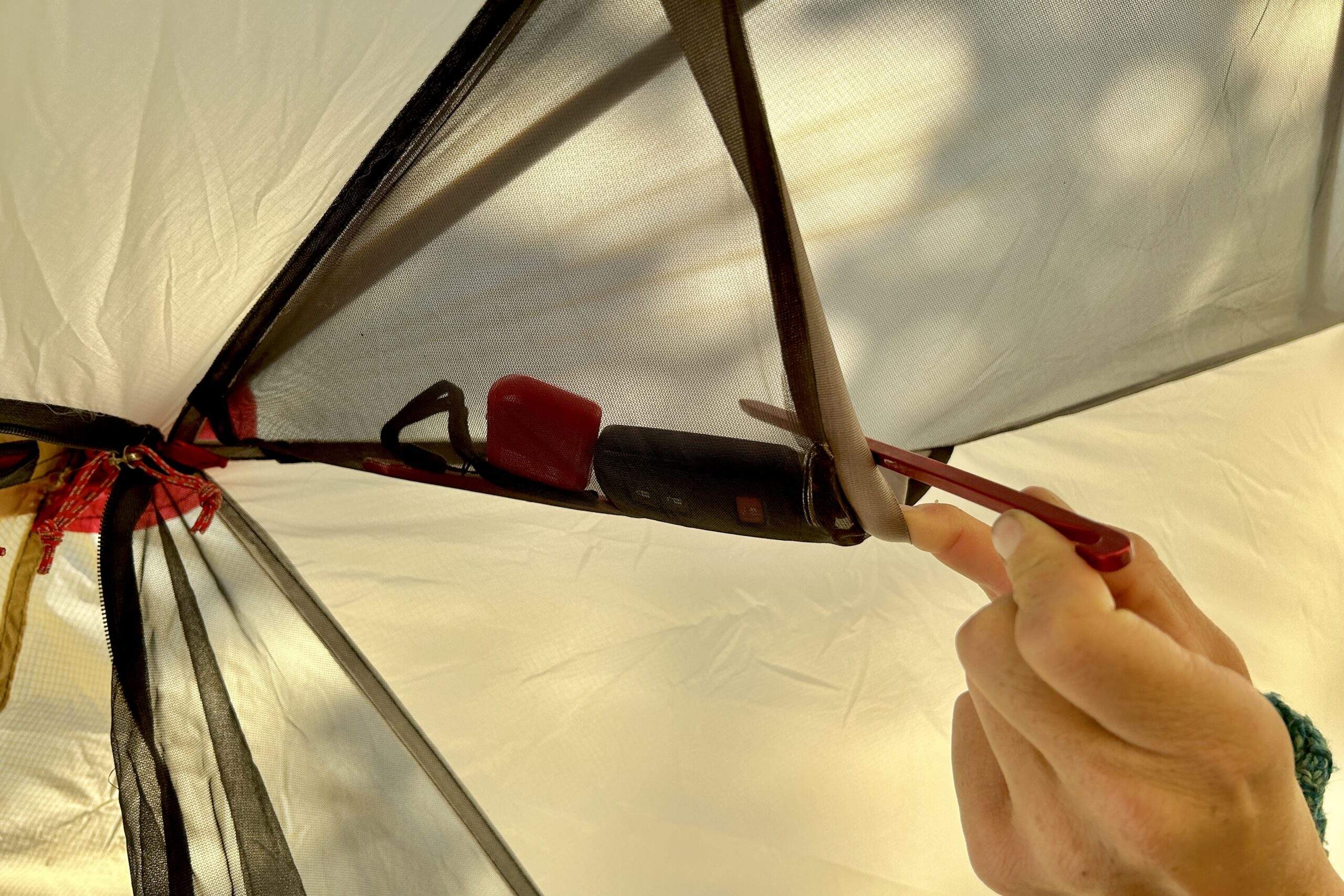 A closeup of the small internal pocket of a tent with items in it.