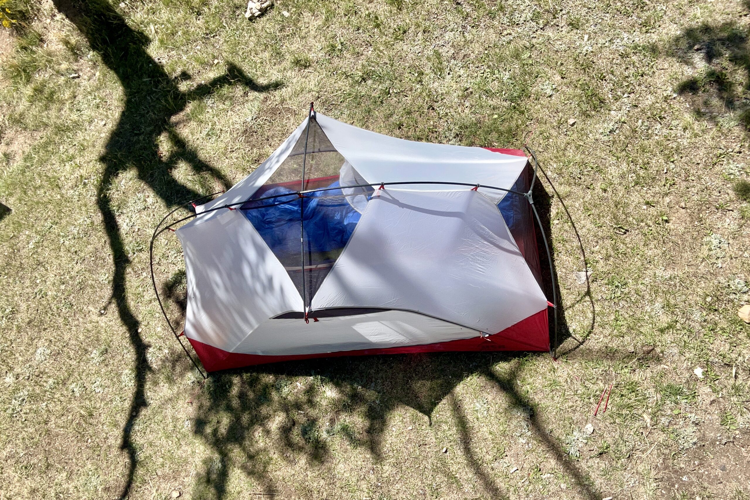 A white and red tent from above in a field.