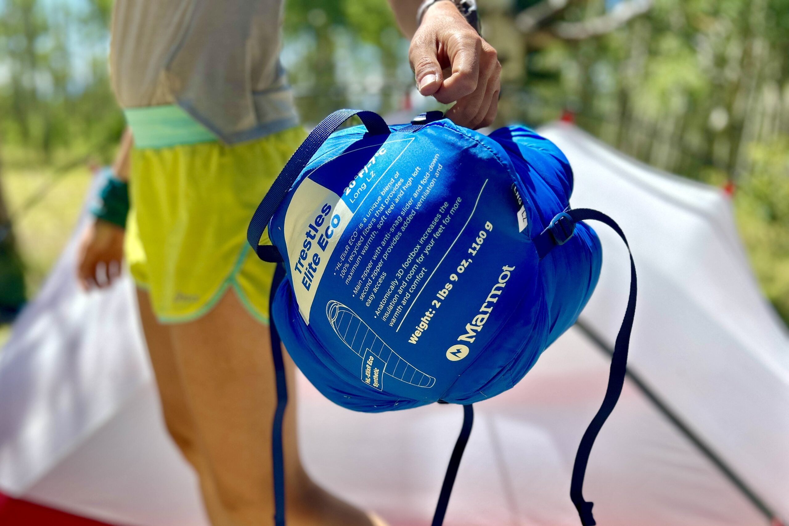 A close-up image of a person holding a sleeping bag stuff sack compressed tightly.