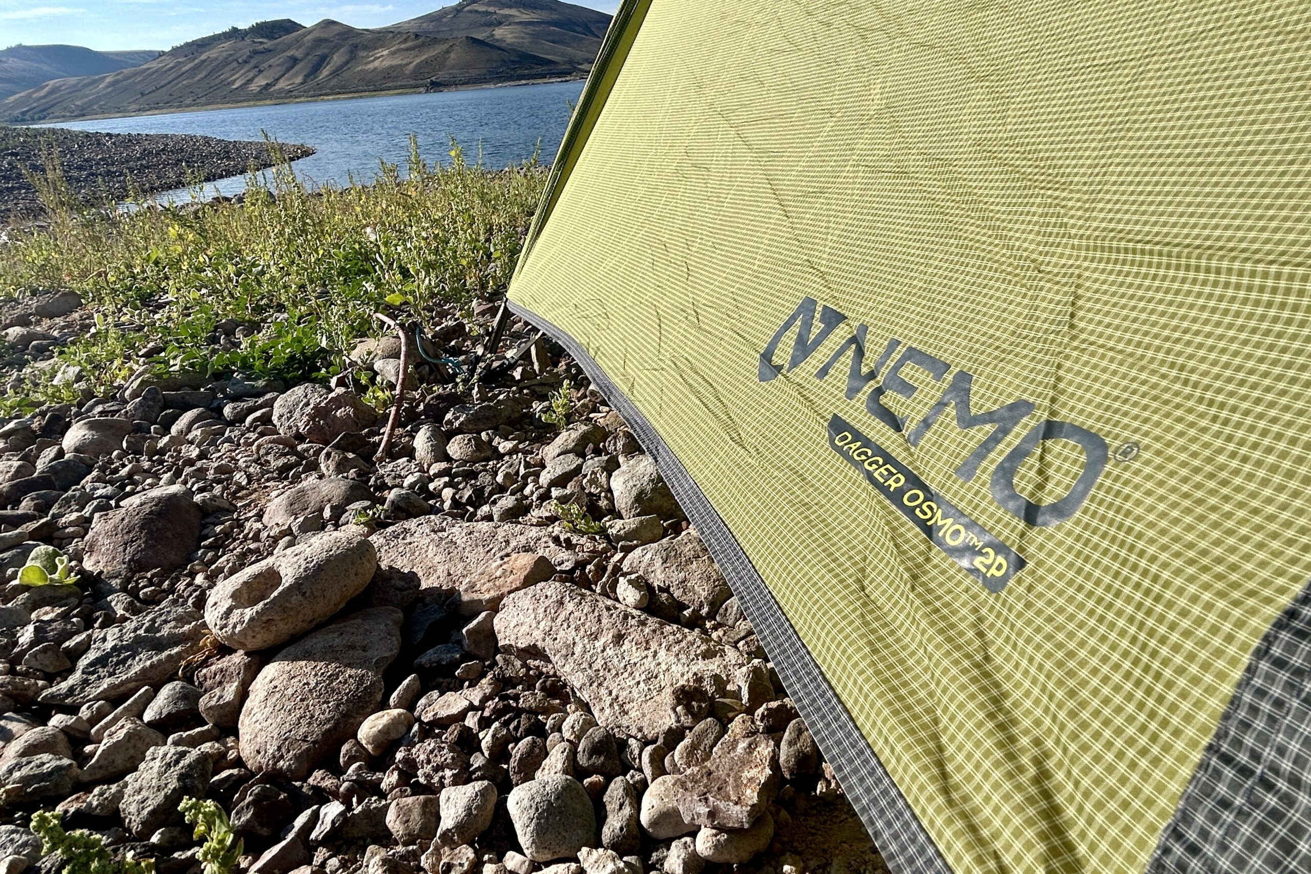 Tent fly of the NEMO Dagger OSMO 2 with a lake and mountains in the background.