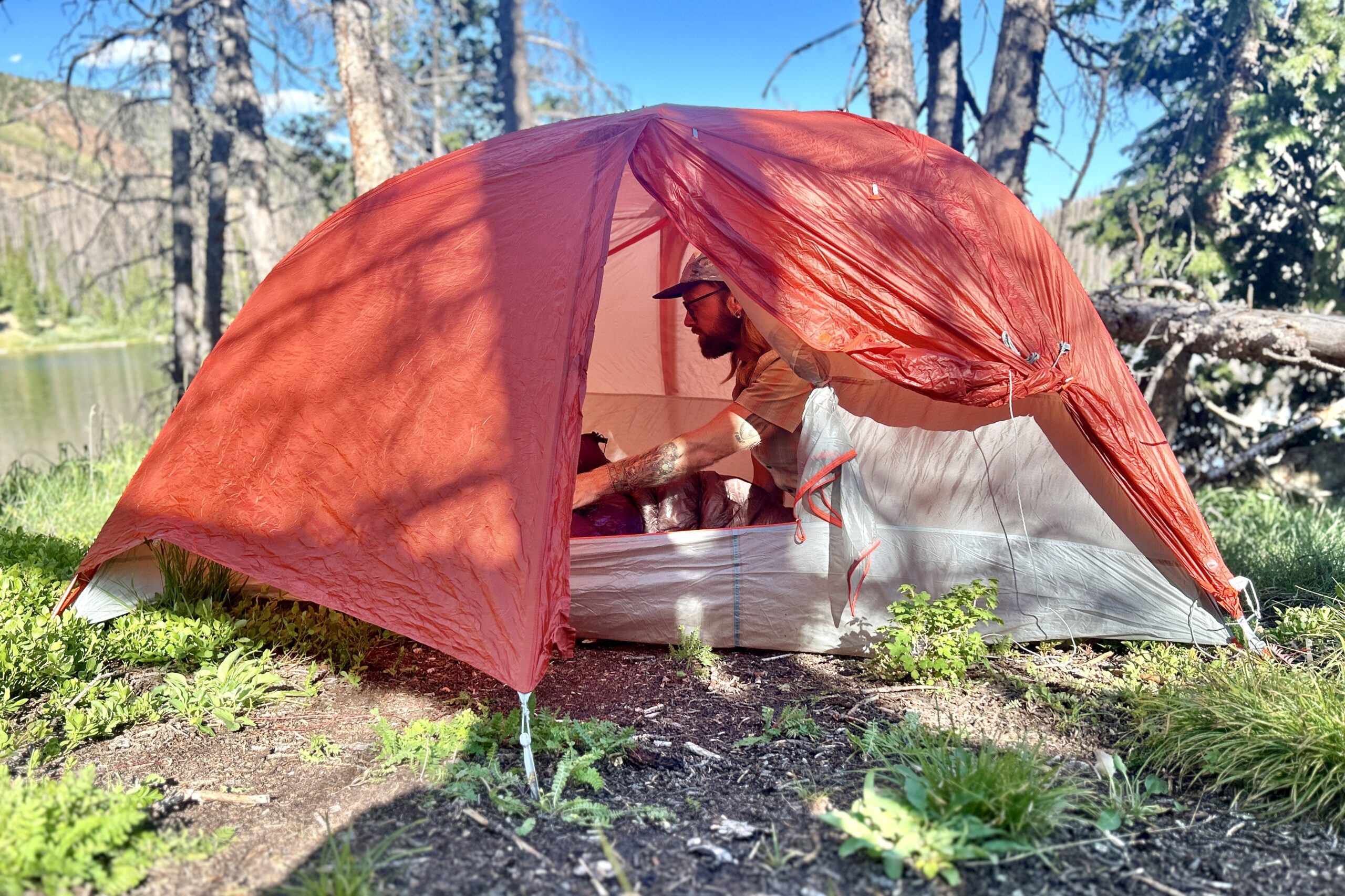 the Big Agnes Copper Spur HV UL2 with the rainfly on and a camper inside the tent. The vestibule door is rolled back and the door is unzipped. 