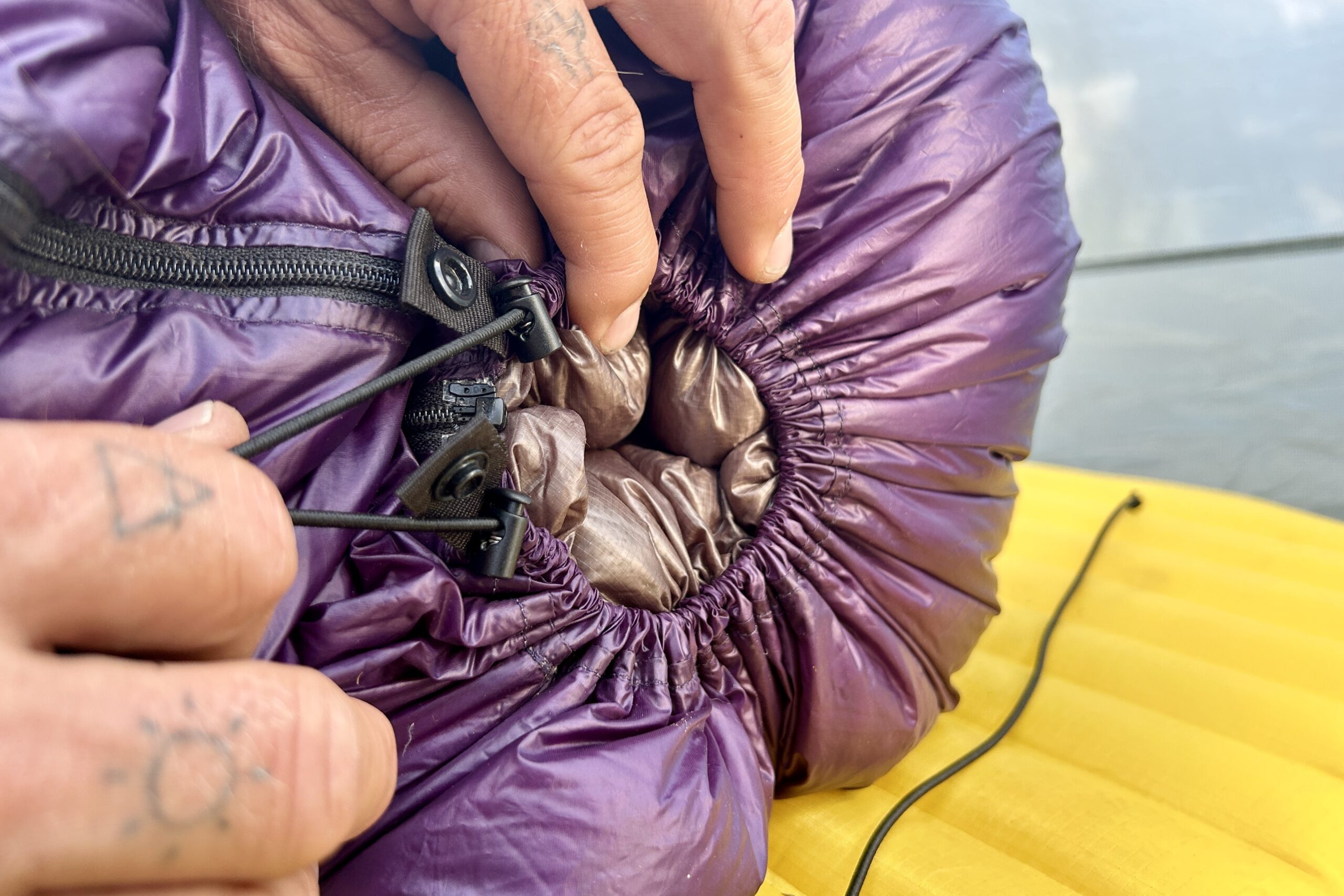 An up-close shot of the footbox of a backpacking quilt fully tightened with cinch cords in view.