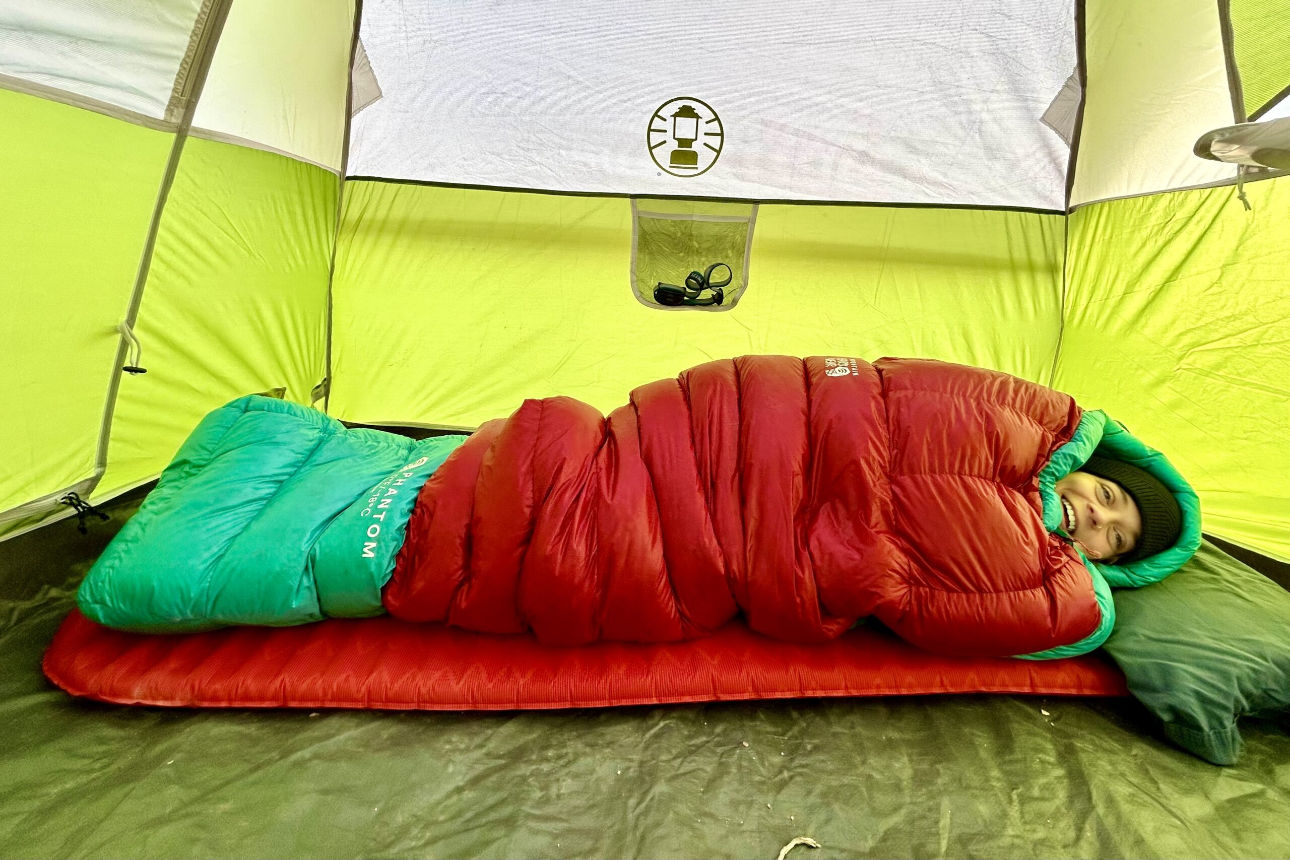 A woman smiles from her sleeping bag in a profile view.