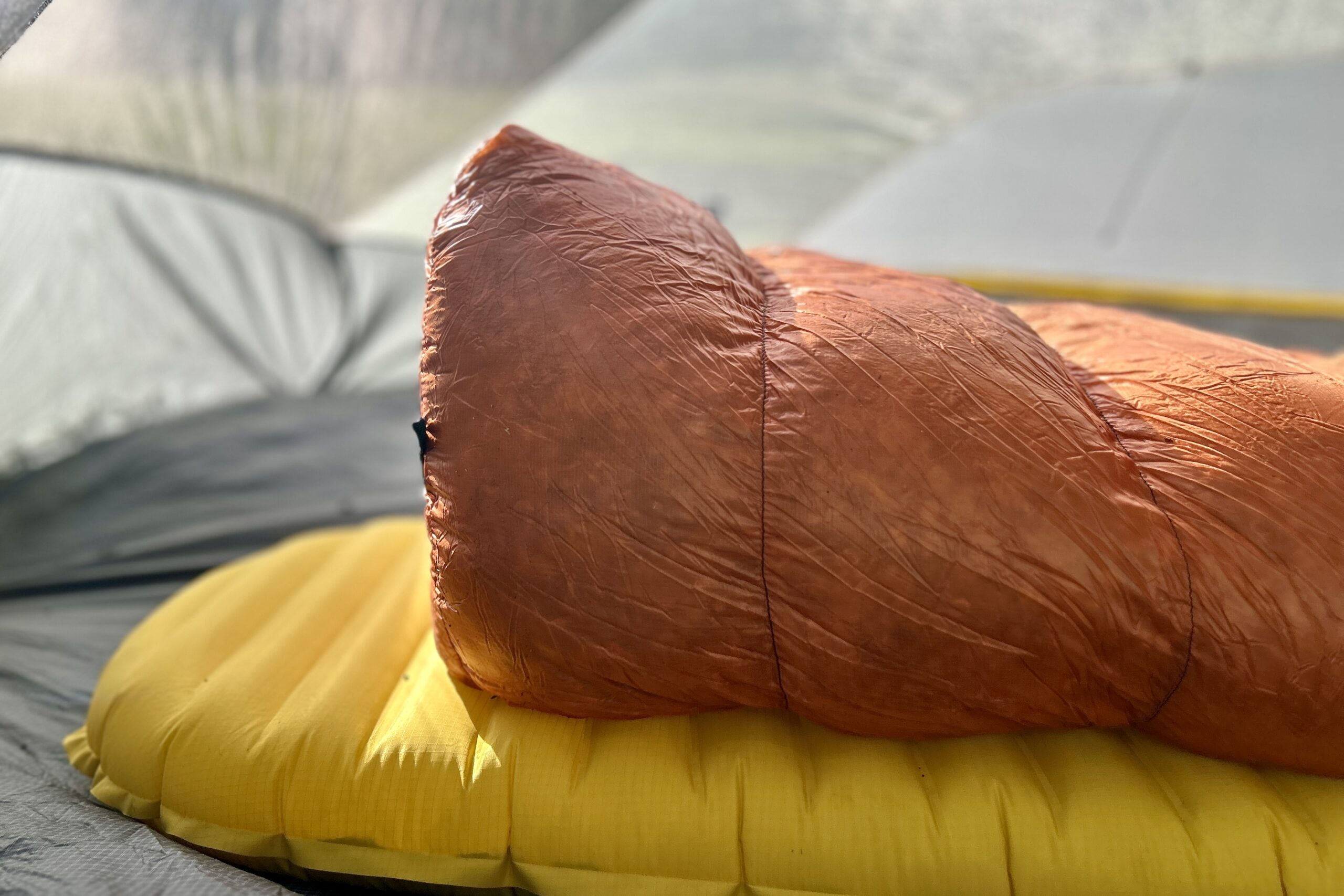 Profile view of the footbox of a sleeping bag on a sleeping pad.