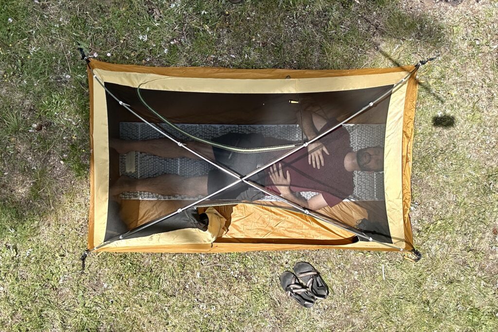 A tent from above with a man laying in it.