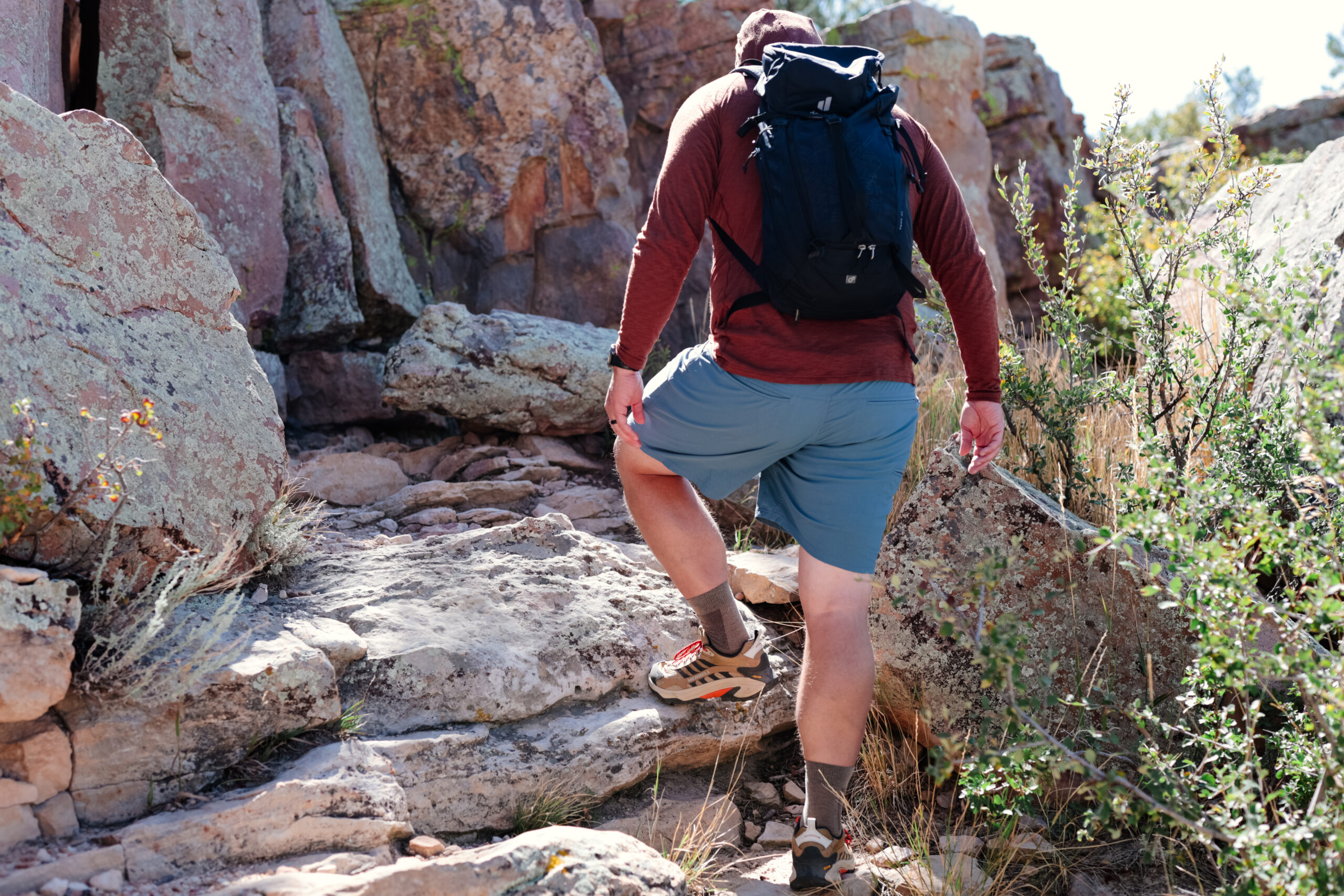 Man steps up on rock in hiking shorts.