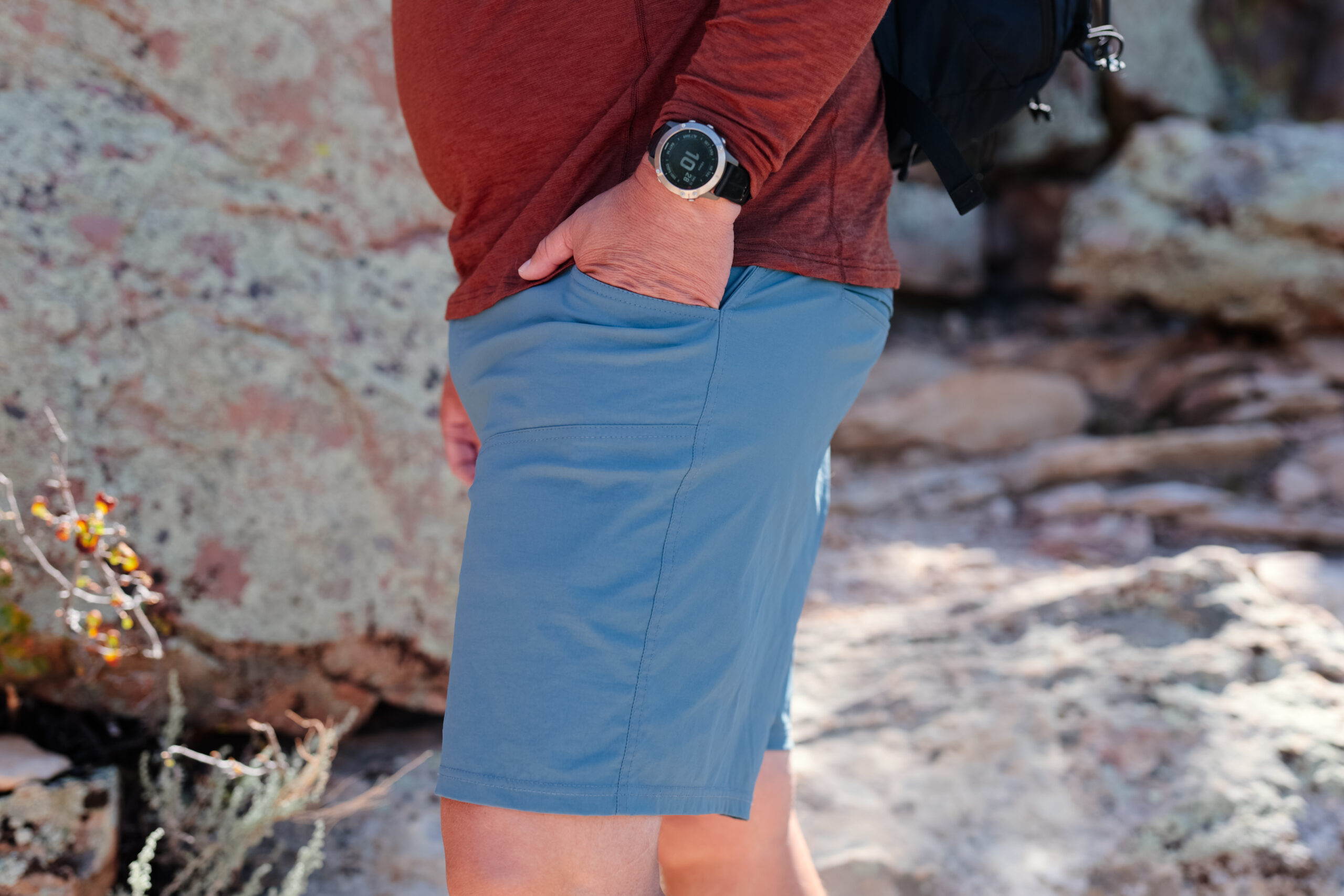 Mão de homem no bolso de um short de caminhada.