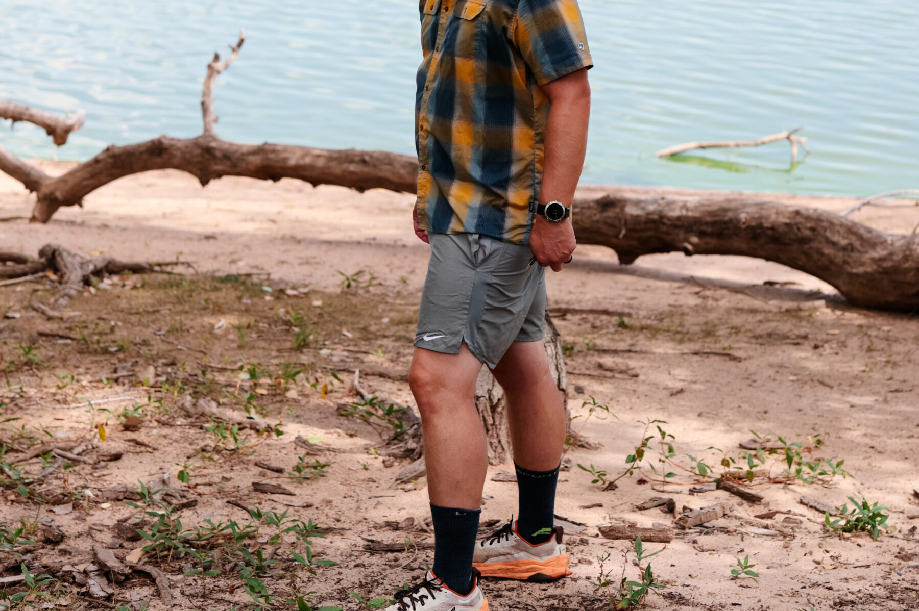 Man walking by a lake in hiking shorts.